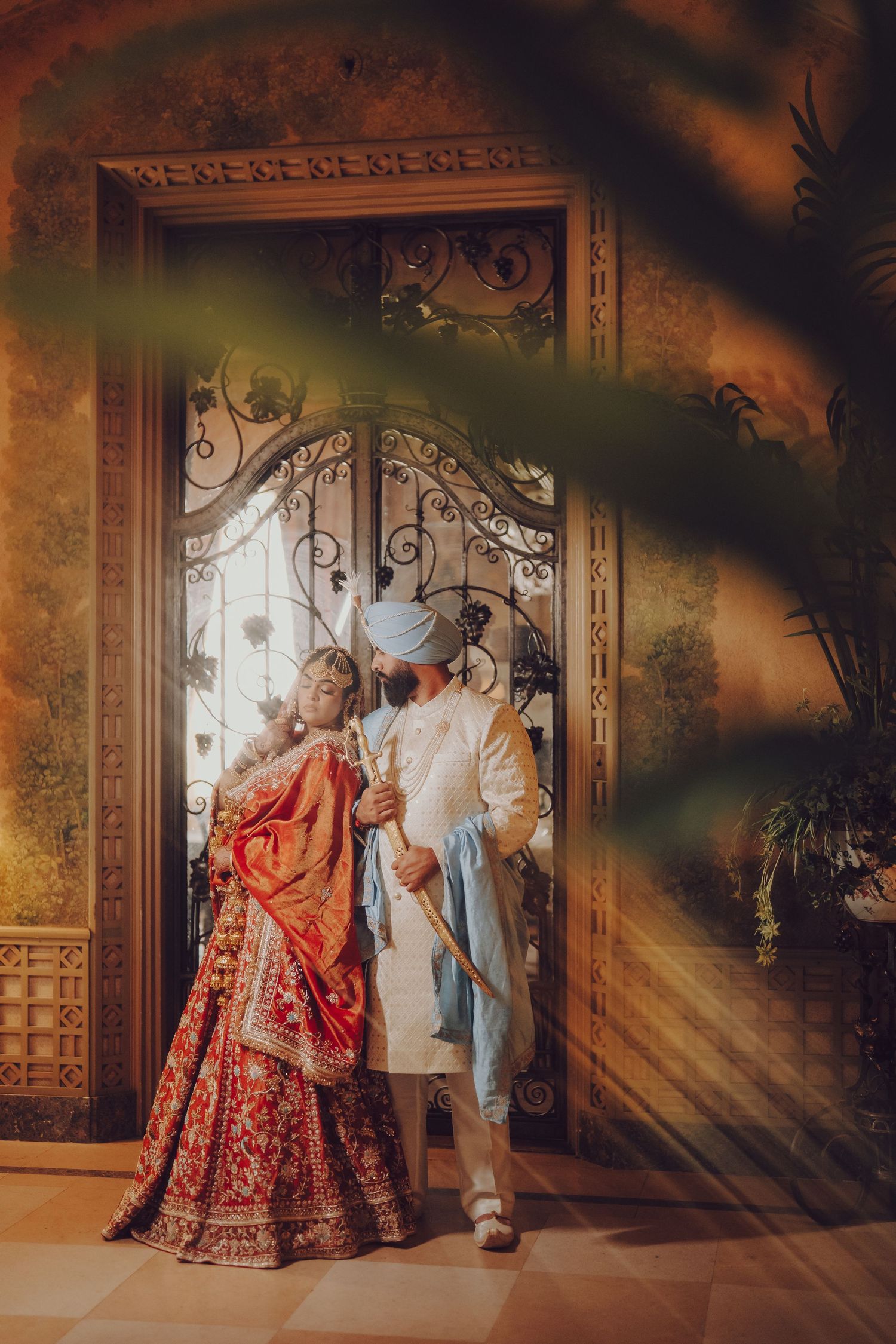 Ornate indoor photoshoot featuring traditional South Asian wedding attire with dramatic lighting.