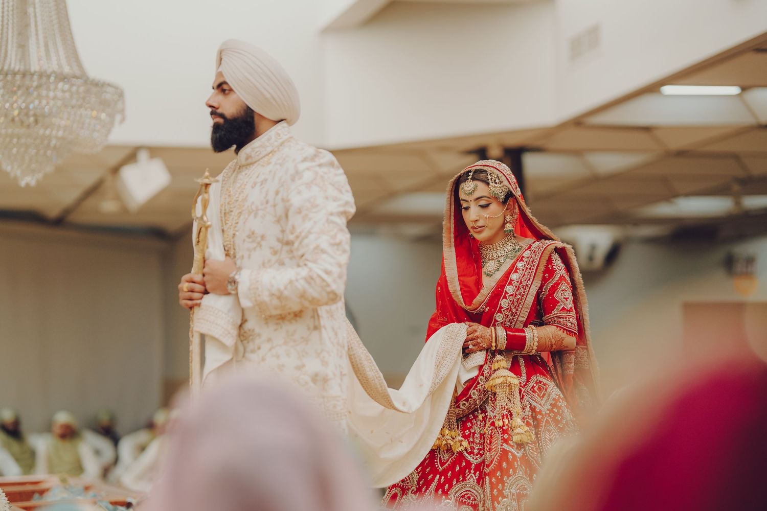 Traditional Indian wedding celebration with guests in formal attire enjoying festivities in an indoor venue.