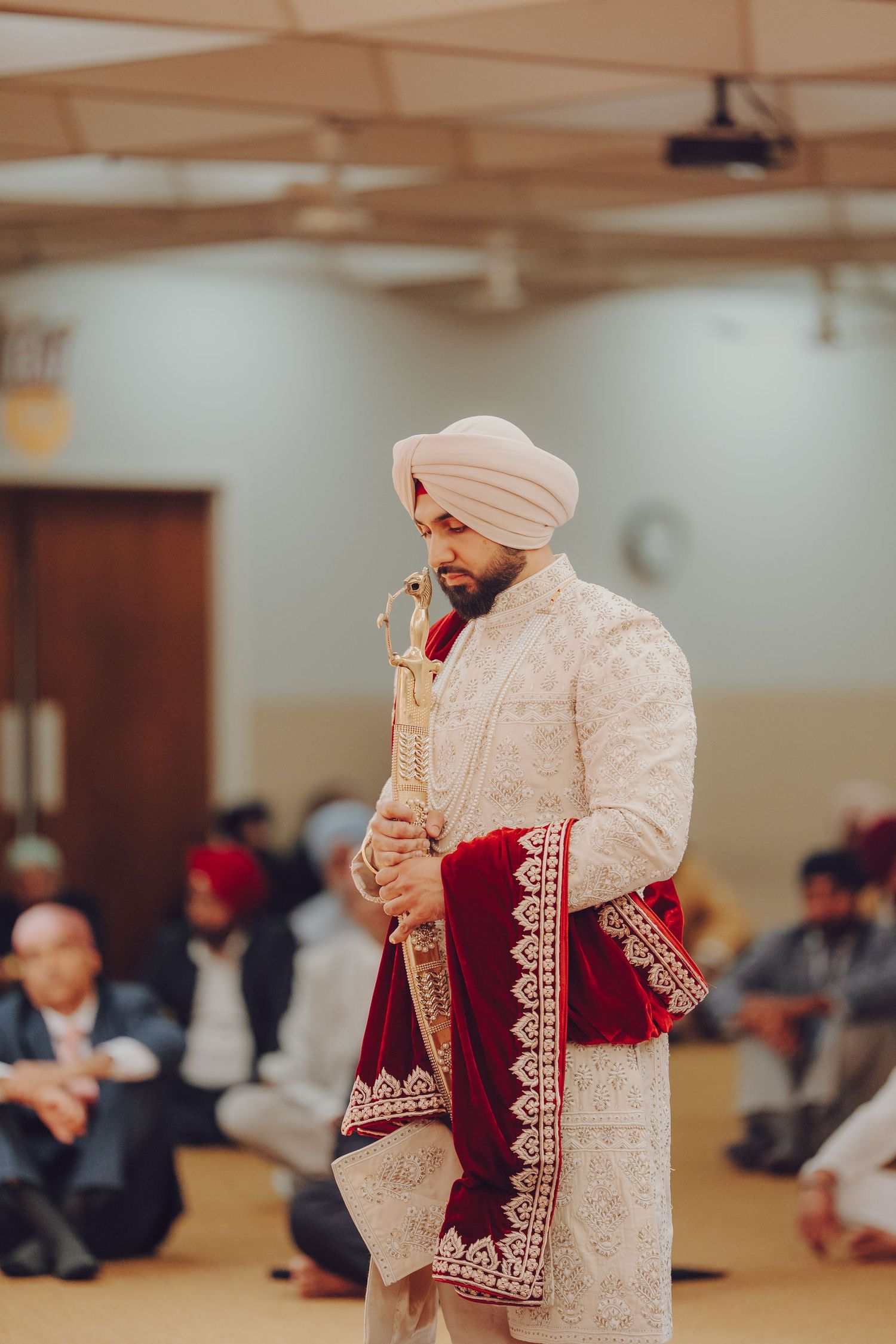 Traditional Sikh wedding ceremony with groom in cream sherwani performing rituals.