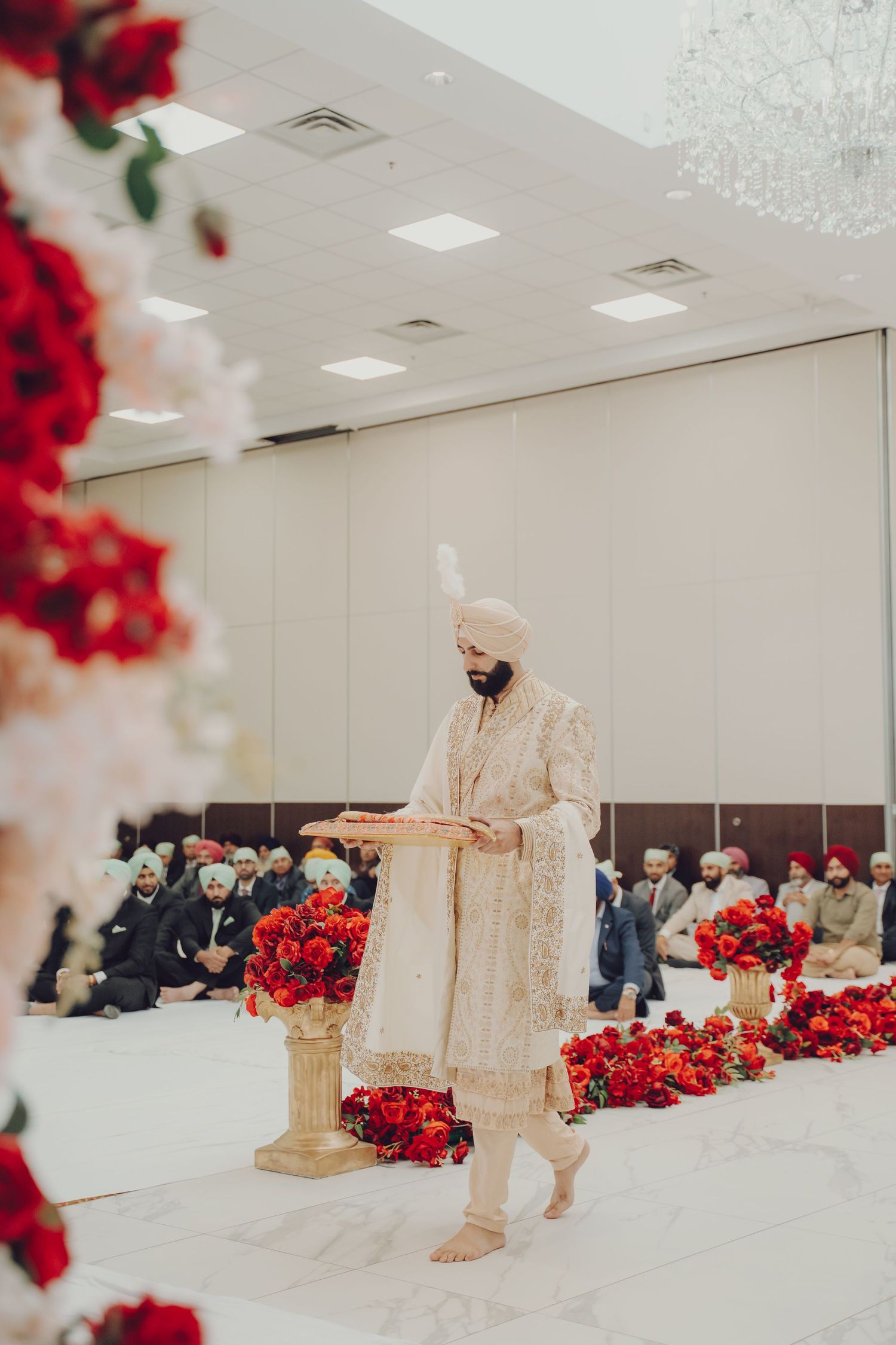 Modern wedding venue with minimalist white walls adorned with red rose arrangements and traditional decor.