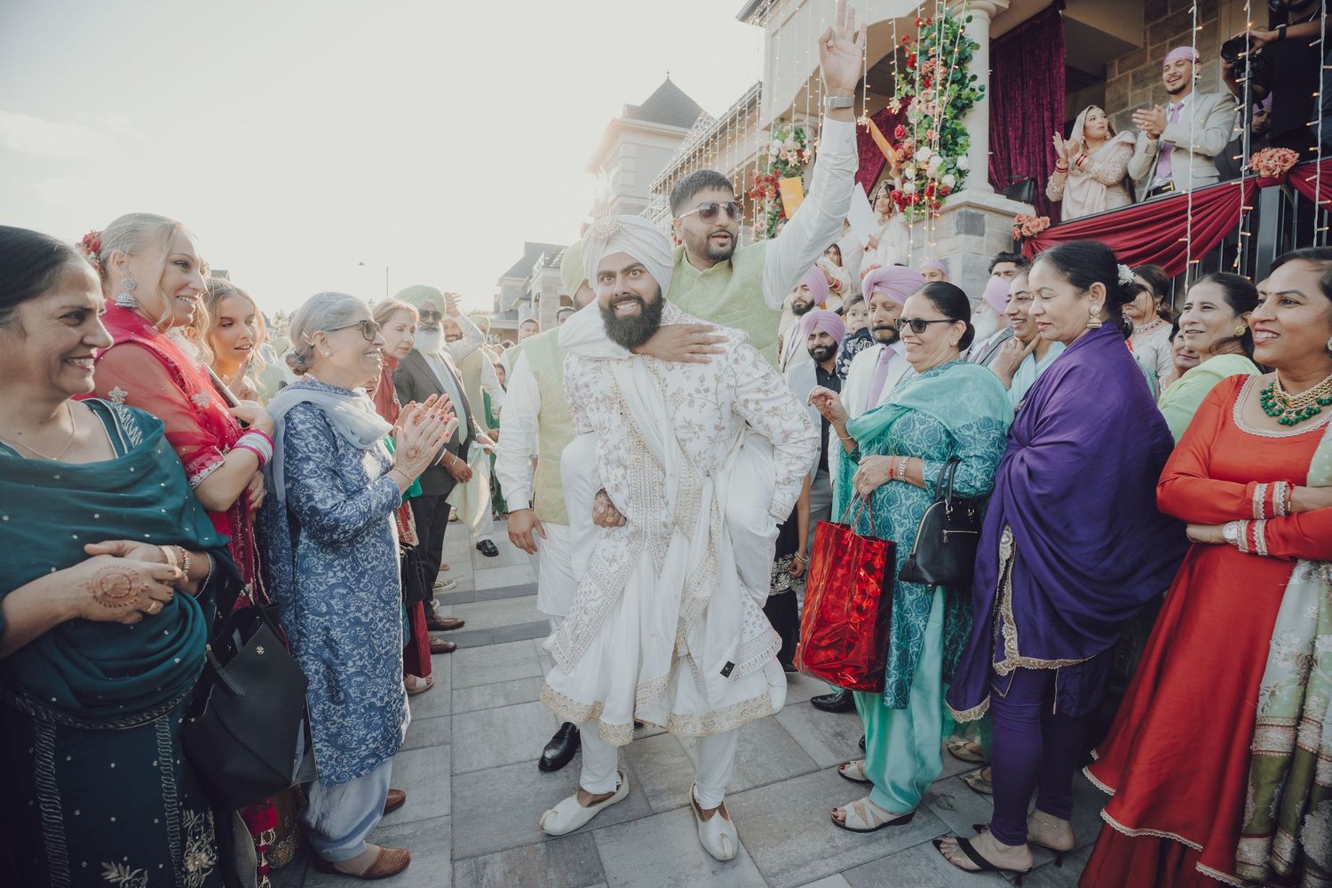 Large group of wedding guests celebrating outside with traditional Indian attire and decorations.