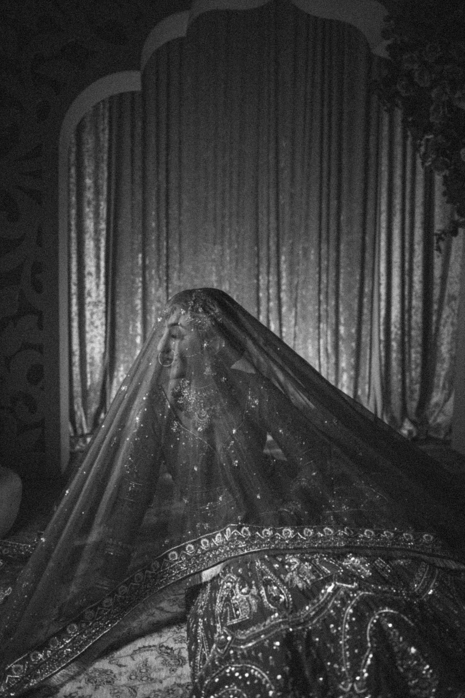 Ornate black and white veil with intricate embroidery and beading against a draped curtain backdrop.