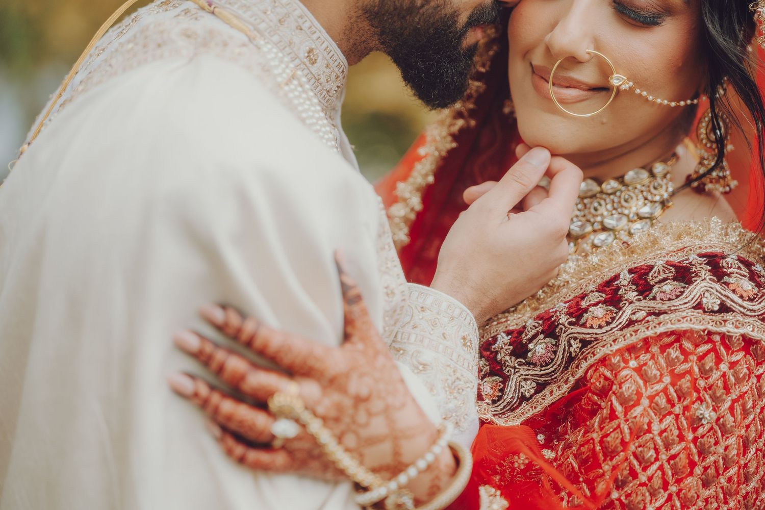 Close-up shot of couple in traditional Indian wedding attire sharing intimate moment.