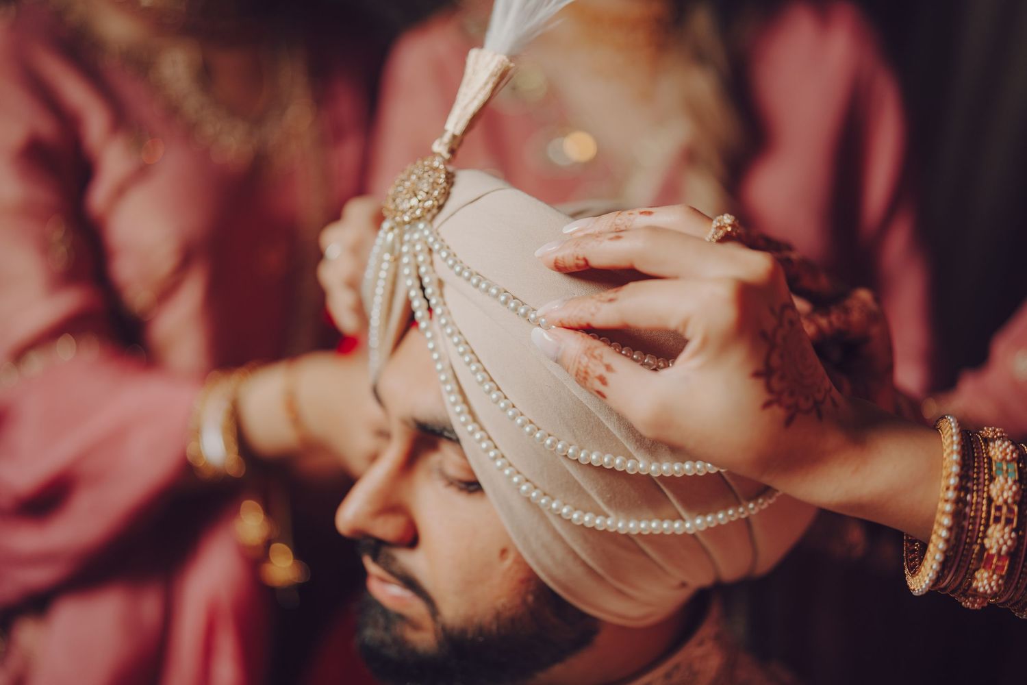 Close-up of ornate bridal jewelry and decorative elements in warm lighting at an Indian wedding.
