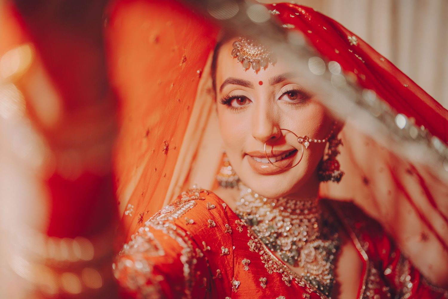 Traditional Indian bridal attire with red dupatta and ornate jewelry in soft natural lighting.
