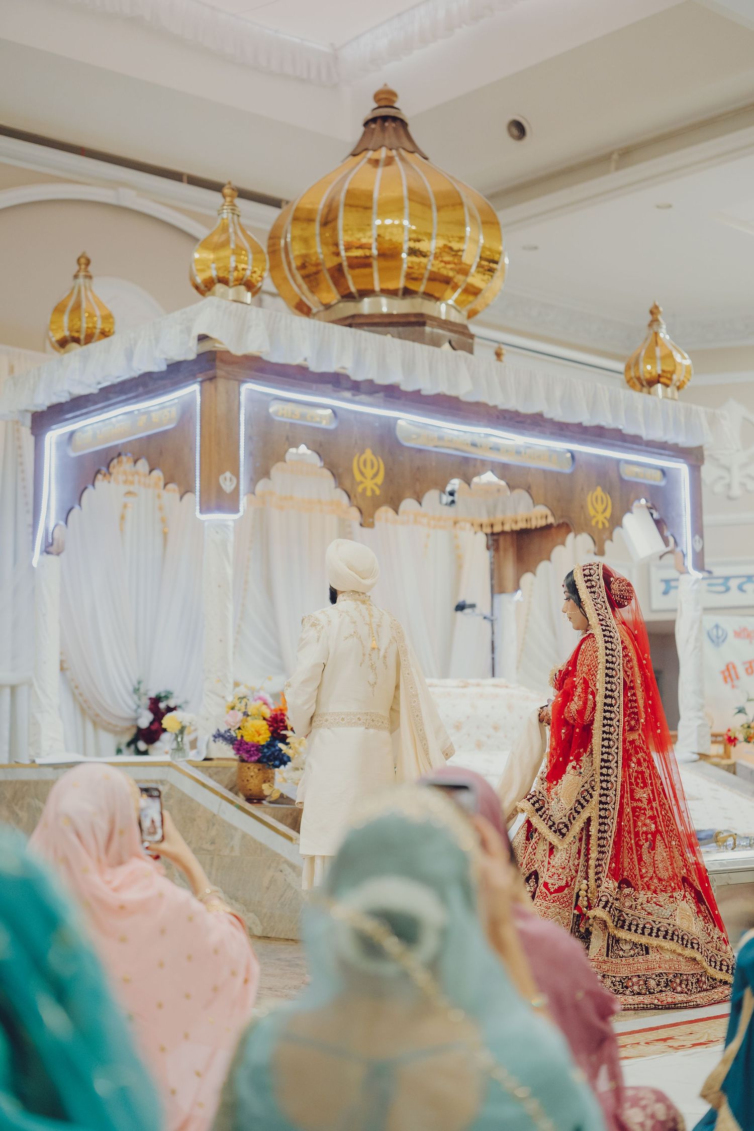 Elegant Indian bridal boutique displaying traditional wedding lehengas and gowns under ornate golden chandeliers.