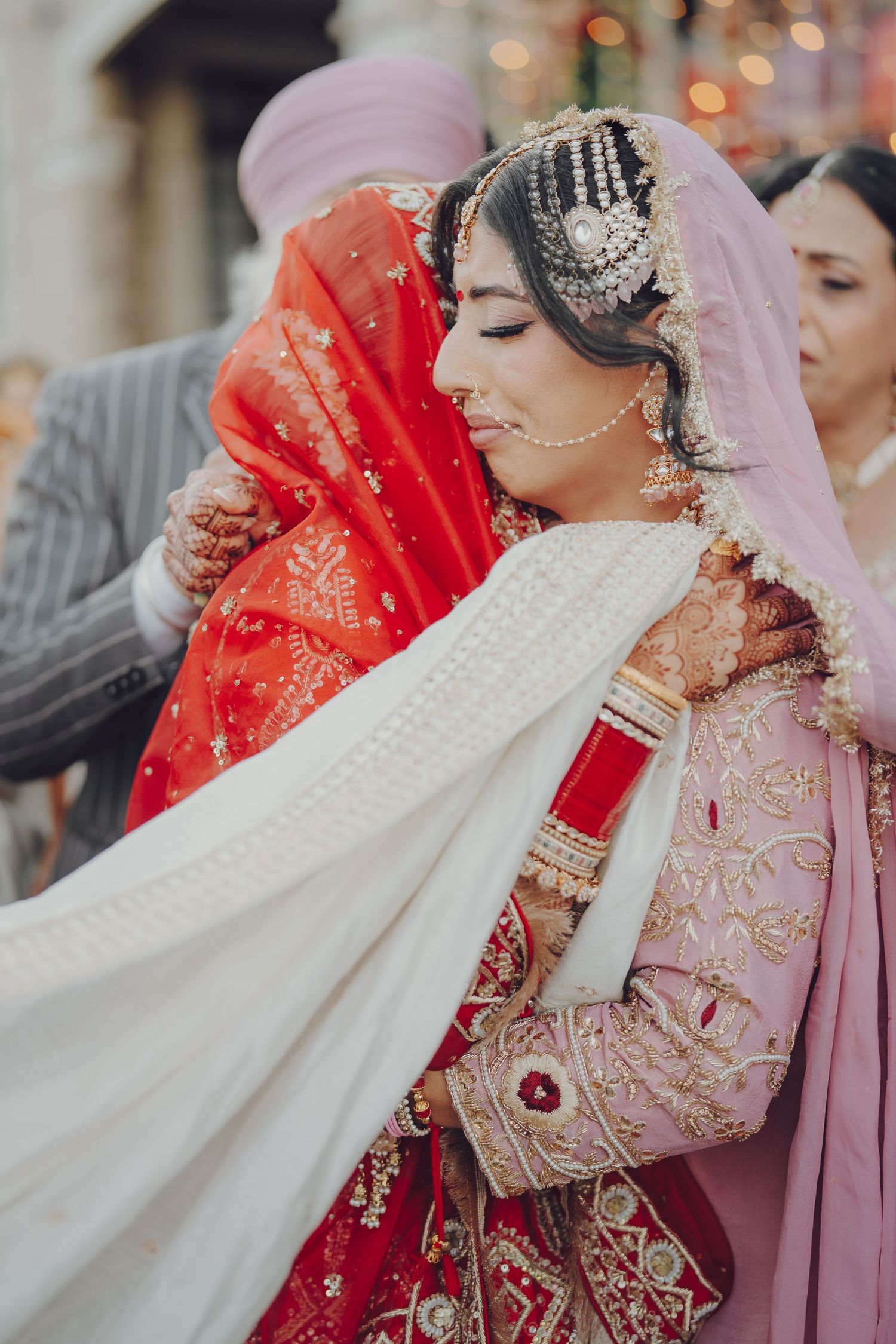 Traditional Indian bridal ceremony with ornate jewelry and pink and red attire details.