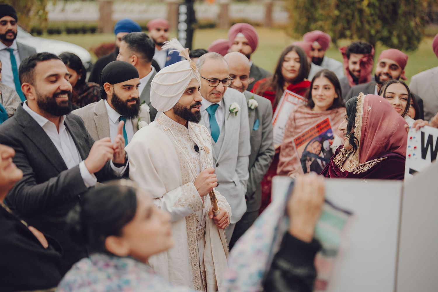 Wedding guests celebrating and taking photos at an outdoor Indian wedding ceremony.