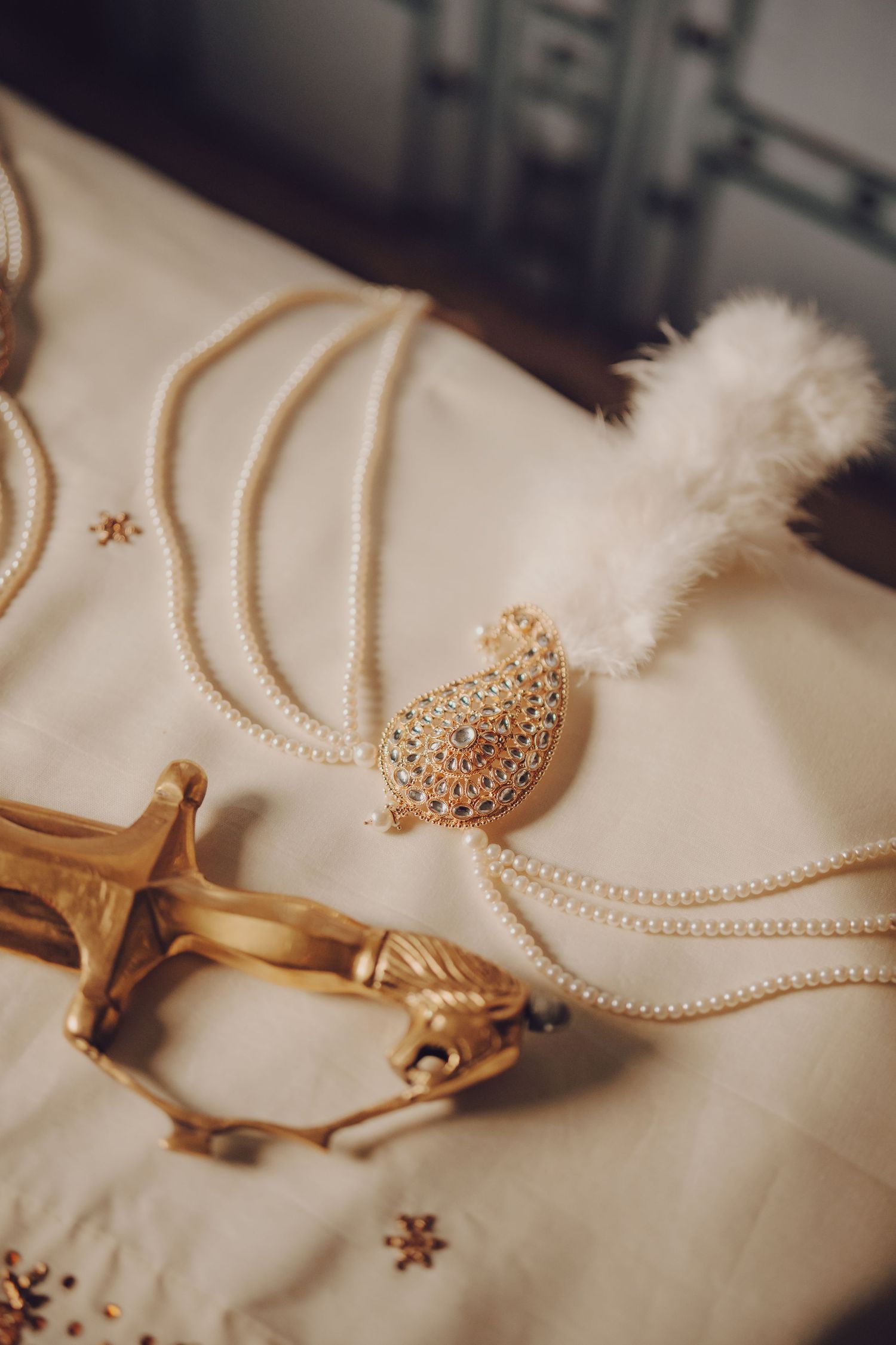 Wedding accessories including gold jewelry and pearl details on cream fabric.