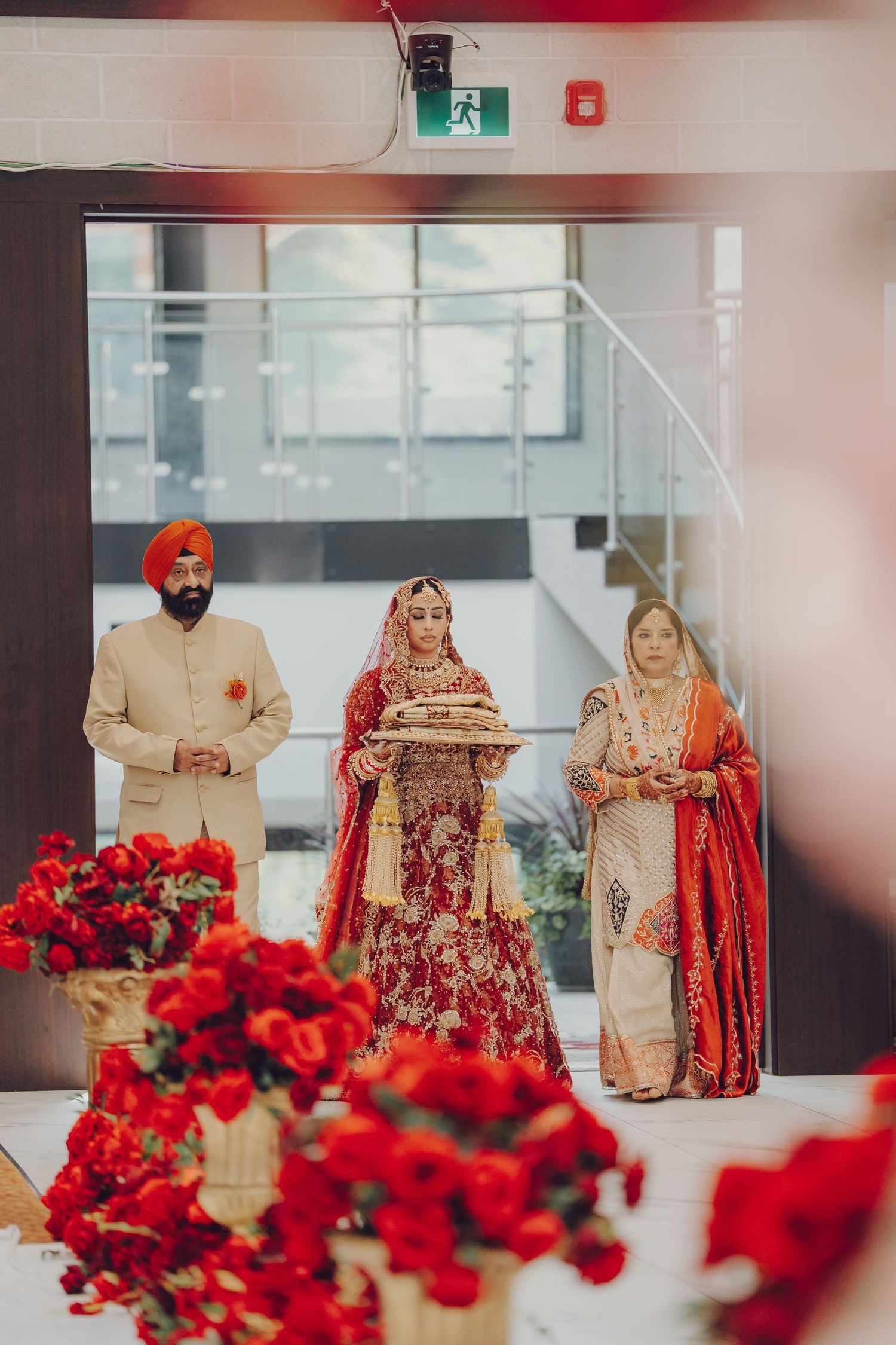 Elegant Sikh wedding ceremony decorated with vibrant red roses and traditional cream and red attire.