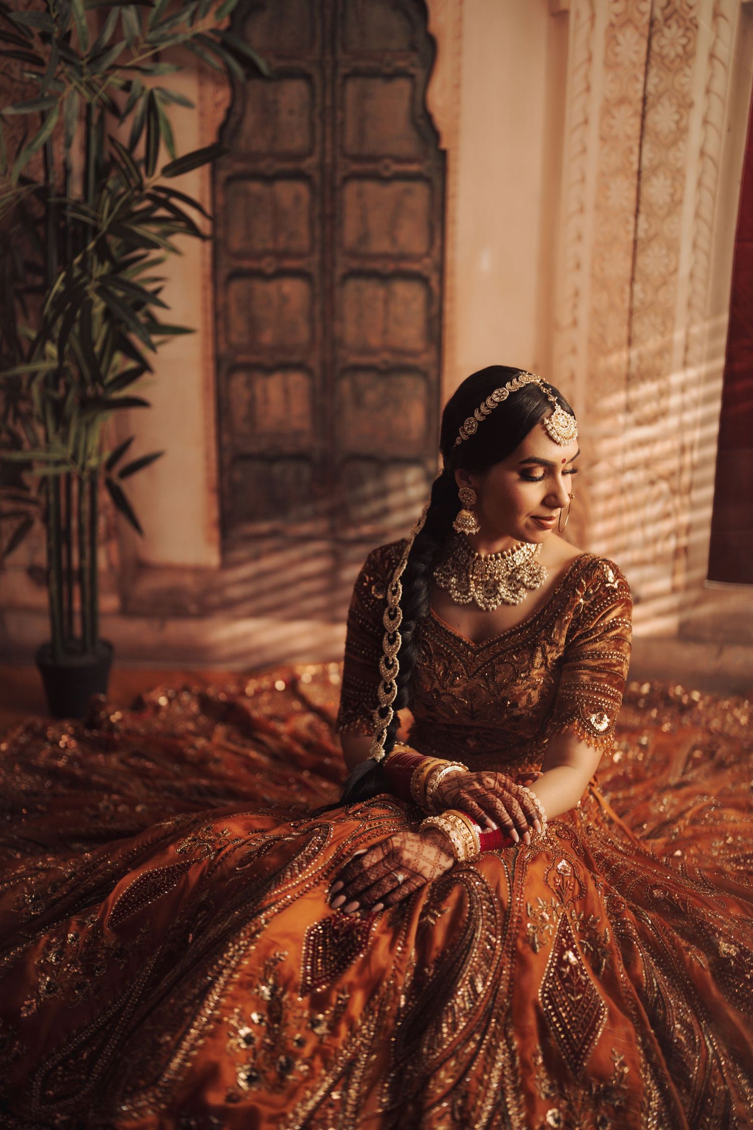 Traditional South Asian bridal attire featuring an ornate gold and burgundy lehenga with intricate embroidery and embellishments.