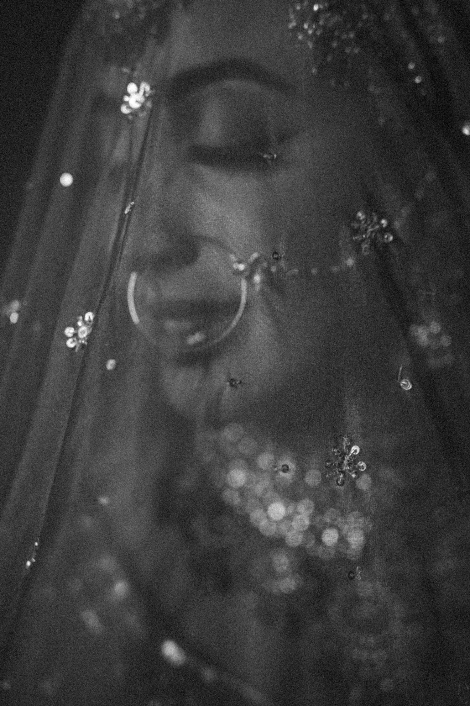 Black and white artistic close-up of bridal details showing sparkles and veil textures.