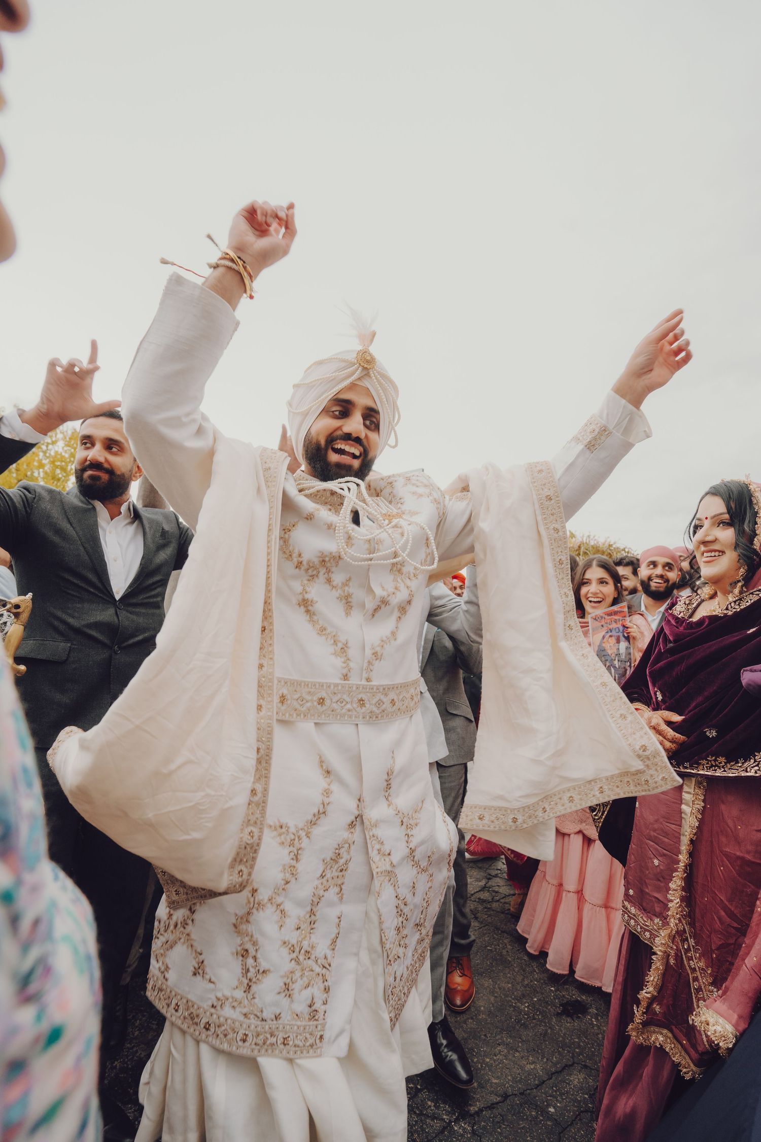 Joyous wedding guests celebrate with raised arms during a traditional Punjabi wedding celebration.