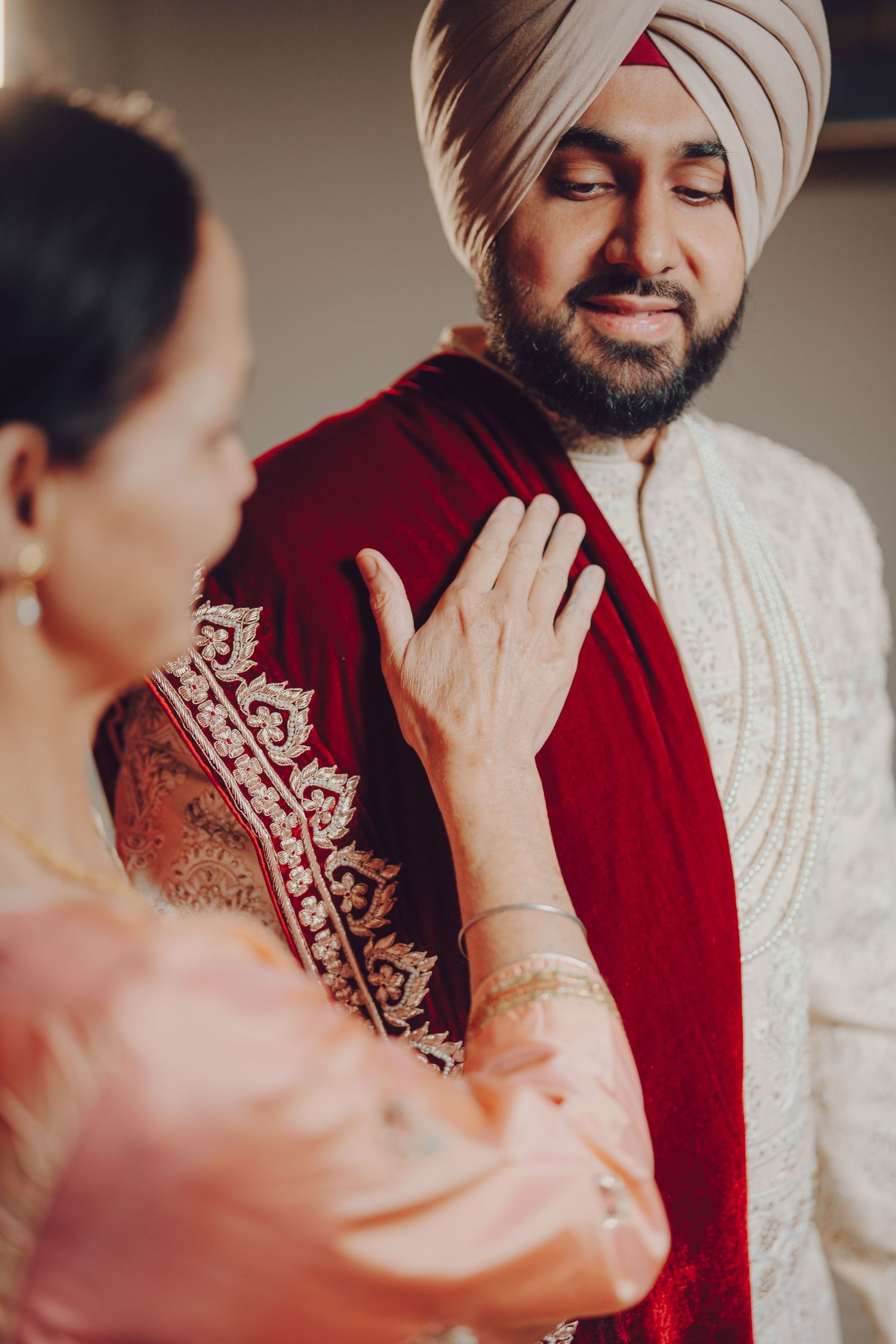 Wedding ceremony moment with groom in traditional Sikh attire and white turban.