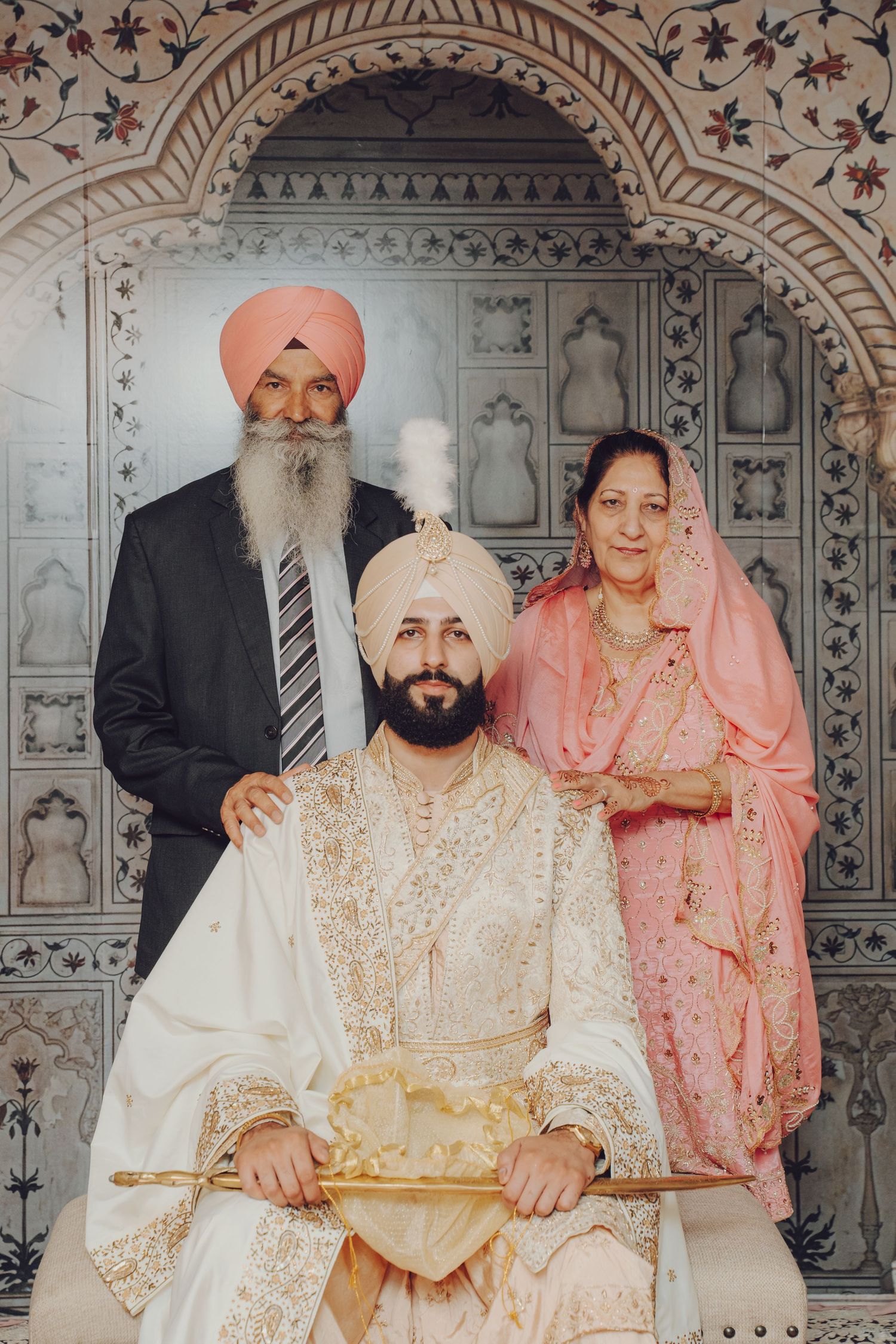 Traditional Sikh wedding ceremony taking place in an ornately decorated temple with architectural details.