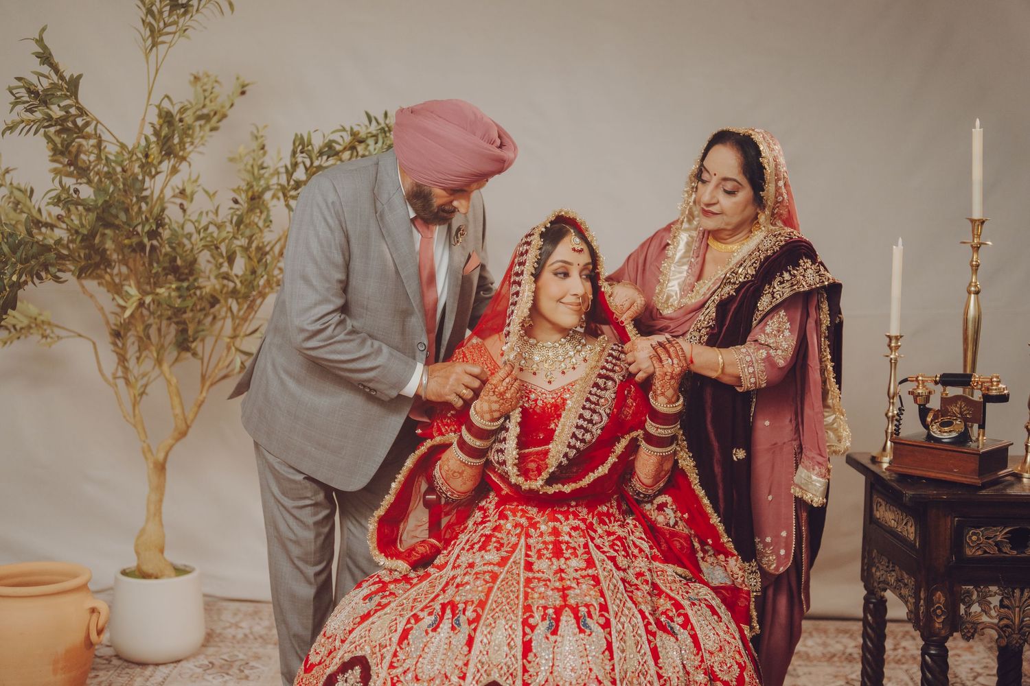 Traditional Indian wedding scene with people in formal attire including a red bridal lehenga and ornate decorations.