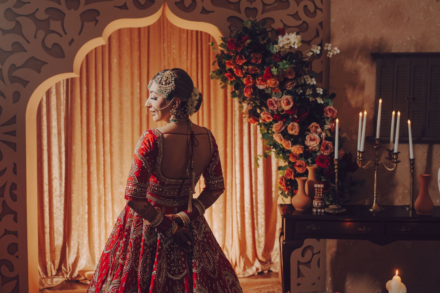 Elegant Christmas photoshoot featuring a dark red velvet dress against a warm-lit backdrop with holiday decorations.