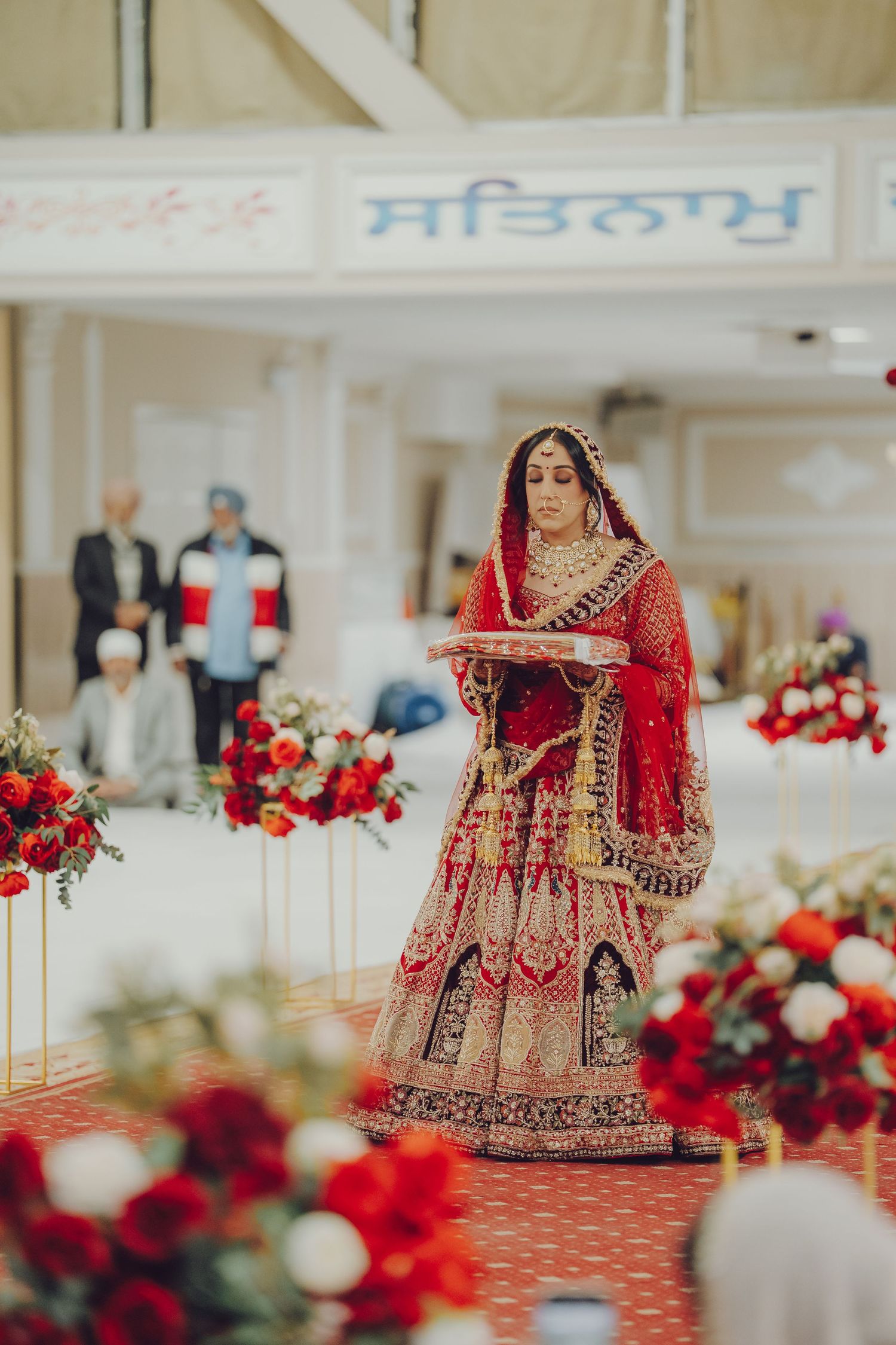 Traditional Indian wedding venue decorated with red and white floral arrangements and elegant table settings.