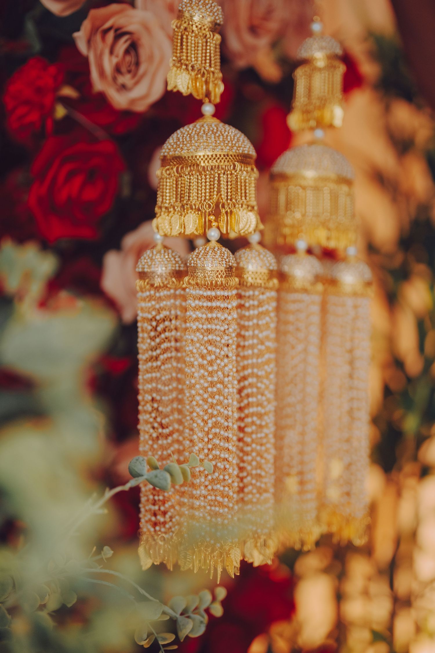 Elegant gold chandelier-style wedding decorations with crystal beading against red roses.
