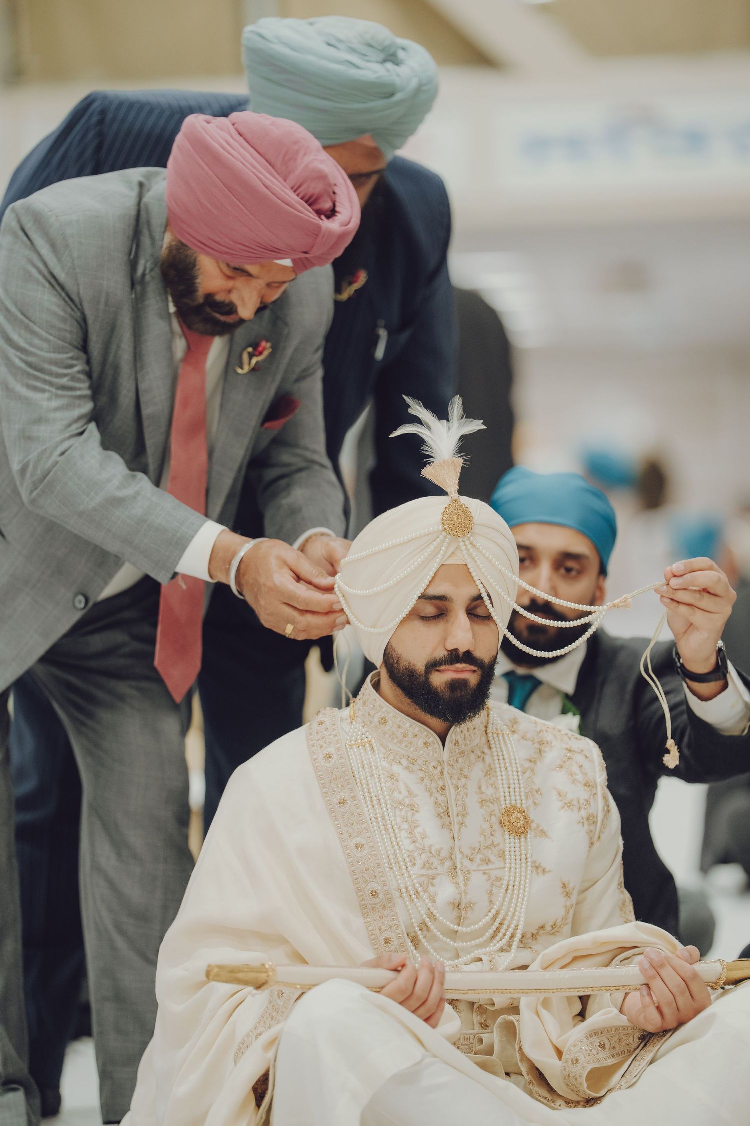A traditional Sikh wedding ceremony shows the groom in white attire during an important ritual moment.