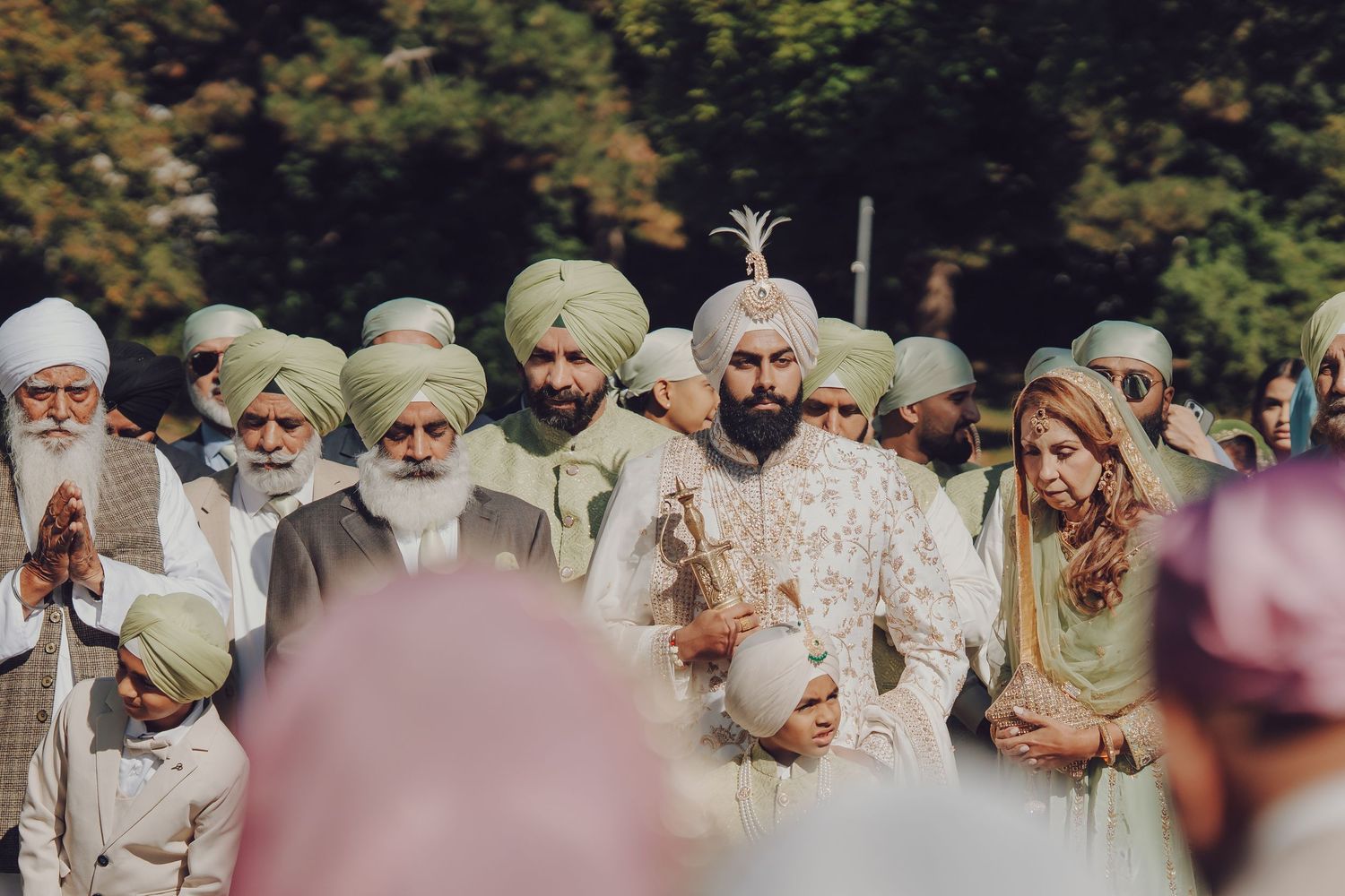 Outdoor Sikh wedding ceremony with guests in traditional turbans and attire gathered together.