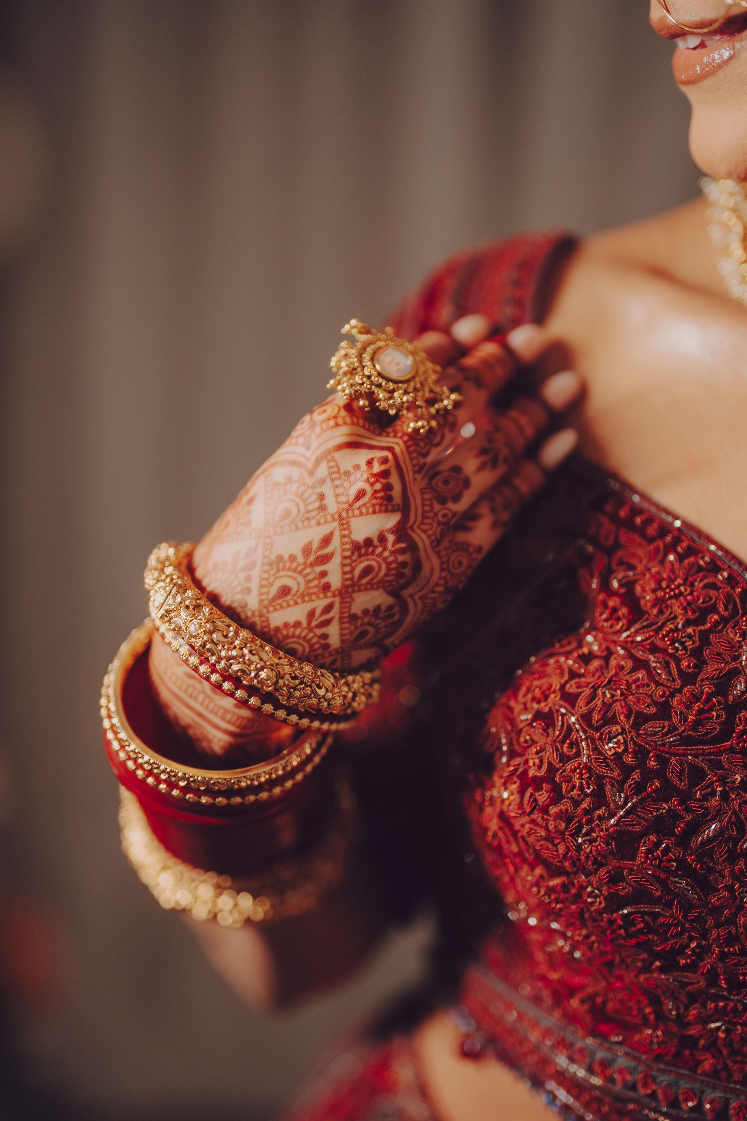 Close-up details of intricate henna designs and gold jewelry on hands adorned in traditional Indian bridal style.