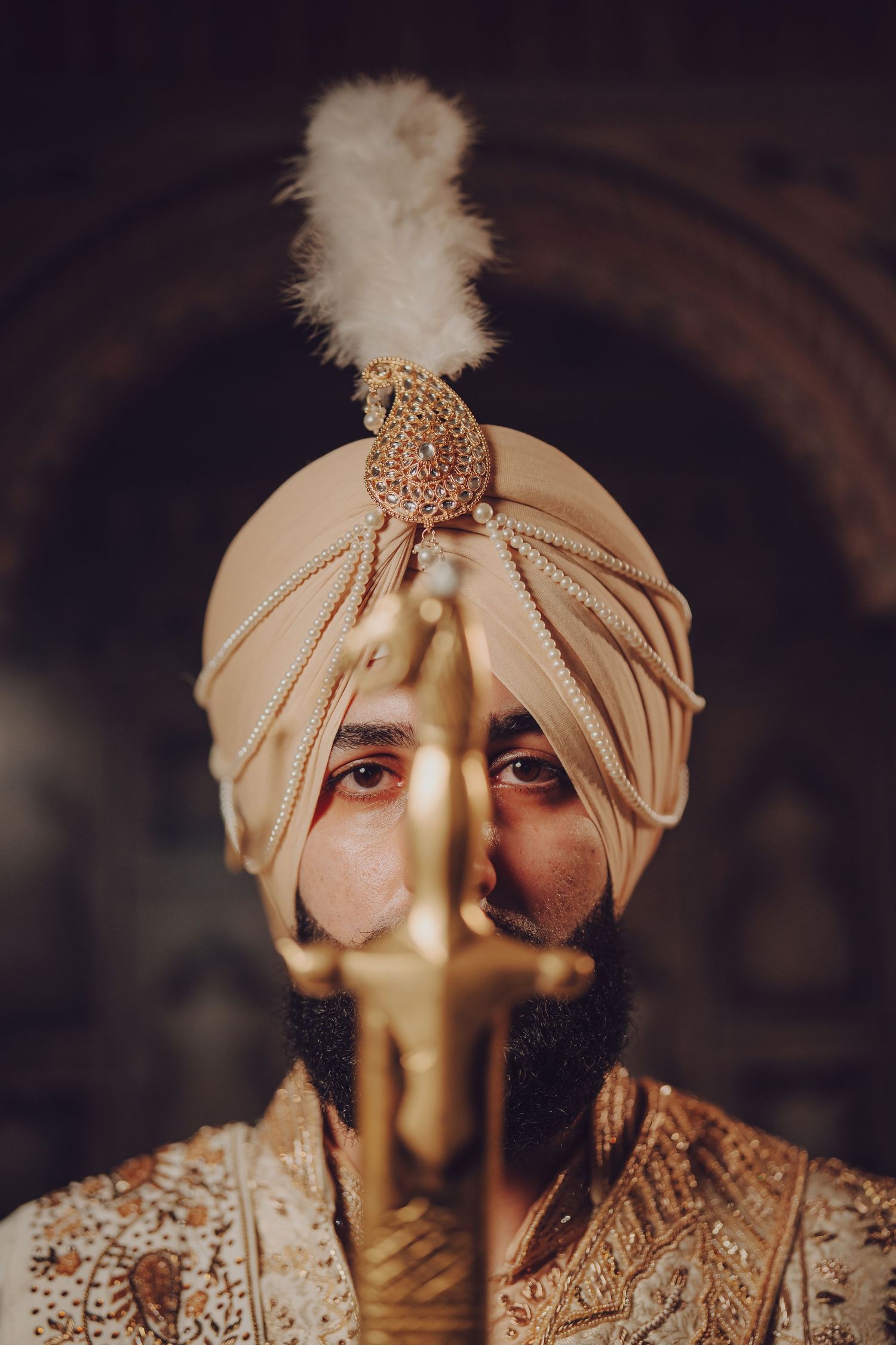 Close-up artistic shot of traditional Indian groom's turban with decorative elements and feather detail.