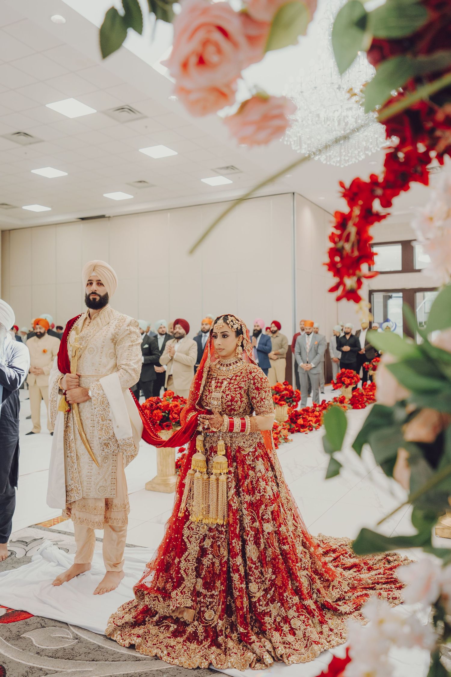 Traditional Indian wedding outfits on display featuring ornate red and gold lehengas with floral decorations.