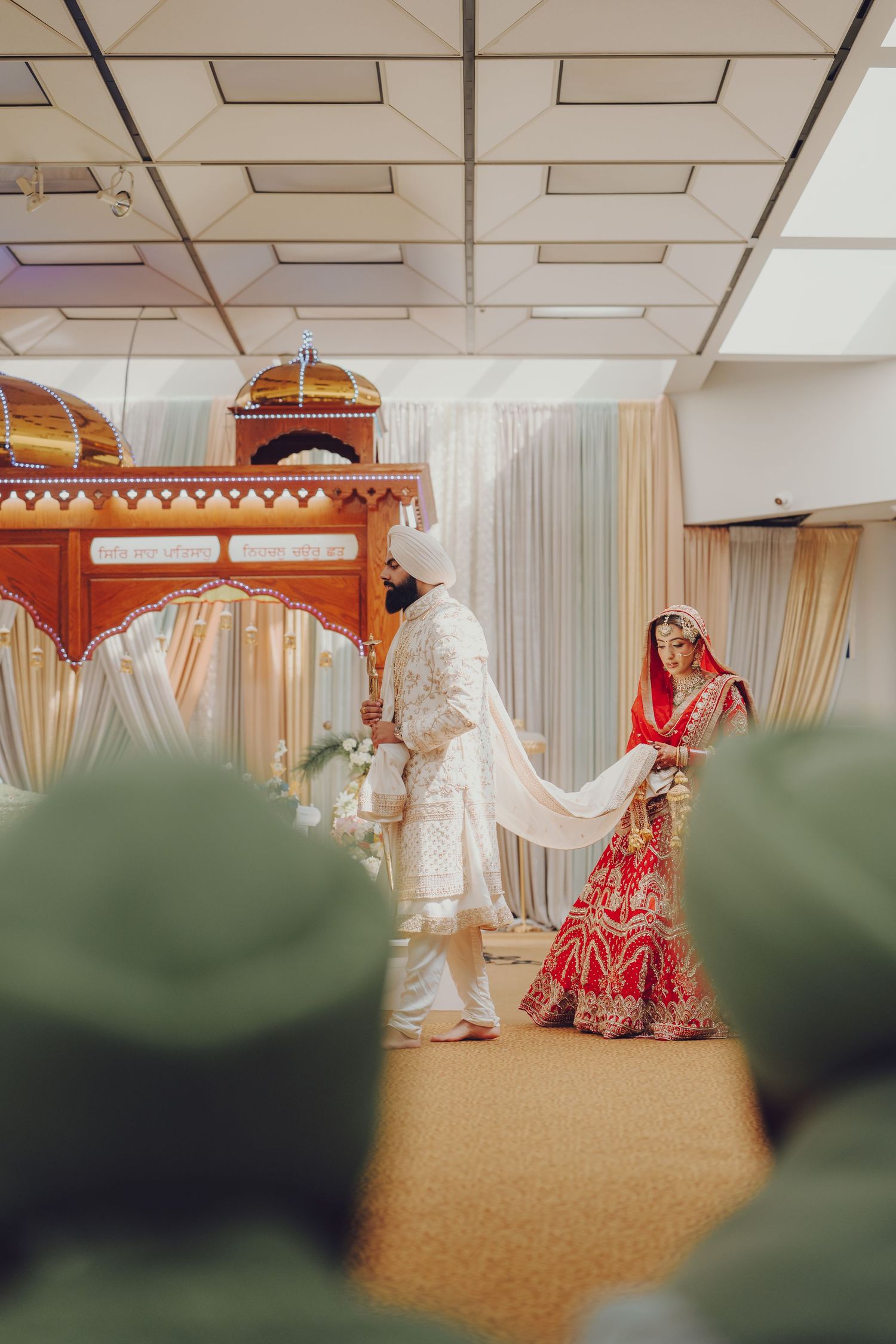 Indian wedding ceremony with couple in traditional attire under decorative mandap structure.