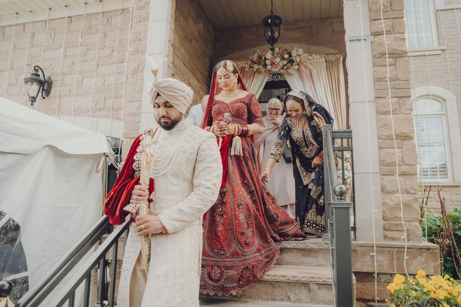Wedding party gathering outside a brick building during a traditional Sikh ceremony.