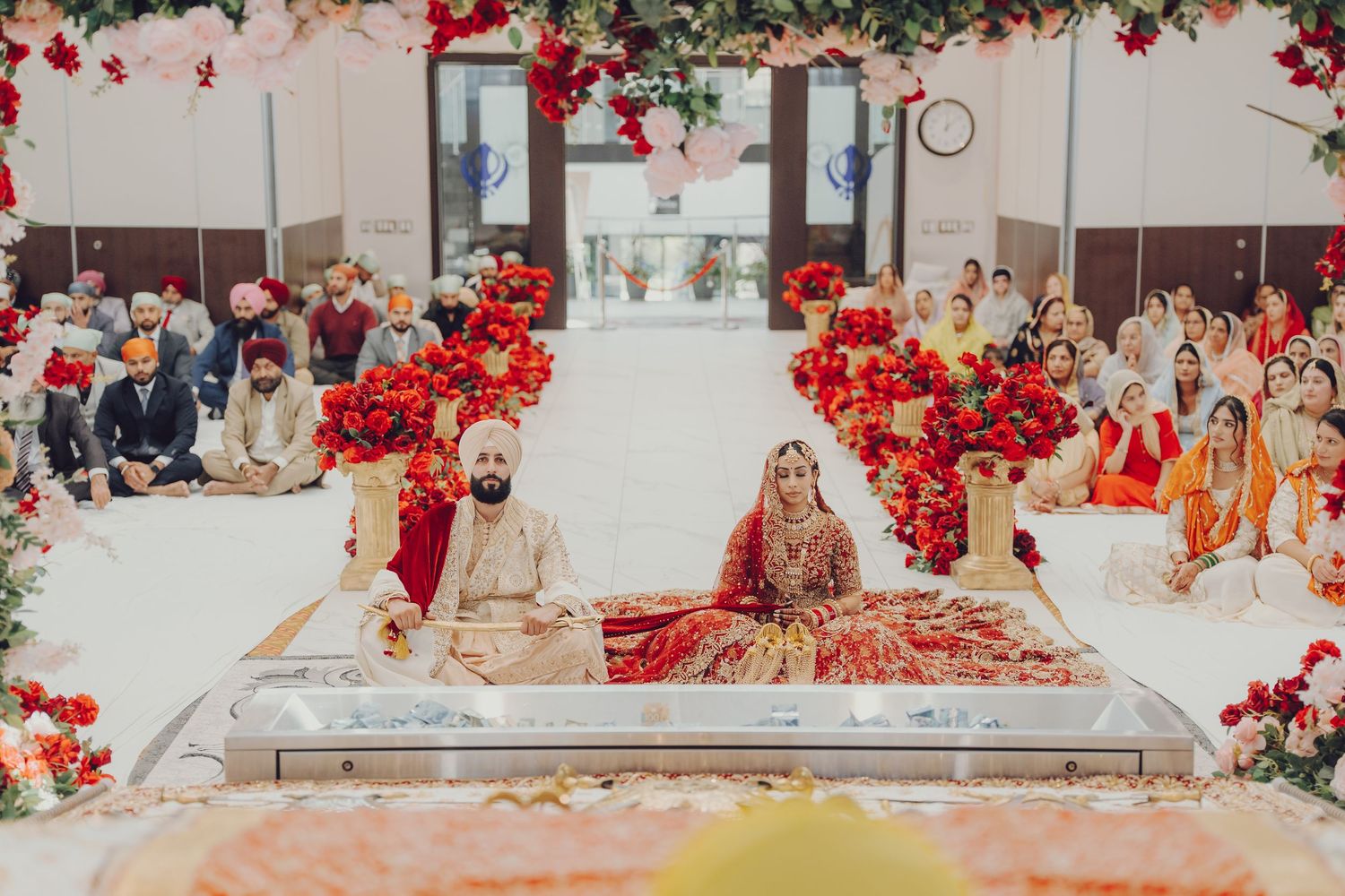 Luxurious wedding venue decorated with vibrant red flowers and elegant gold accents for an Indian celebration.