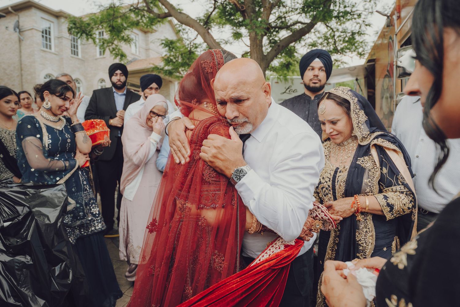 Wedding celebration with guests gathering around luxury cars and traditional decorations.