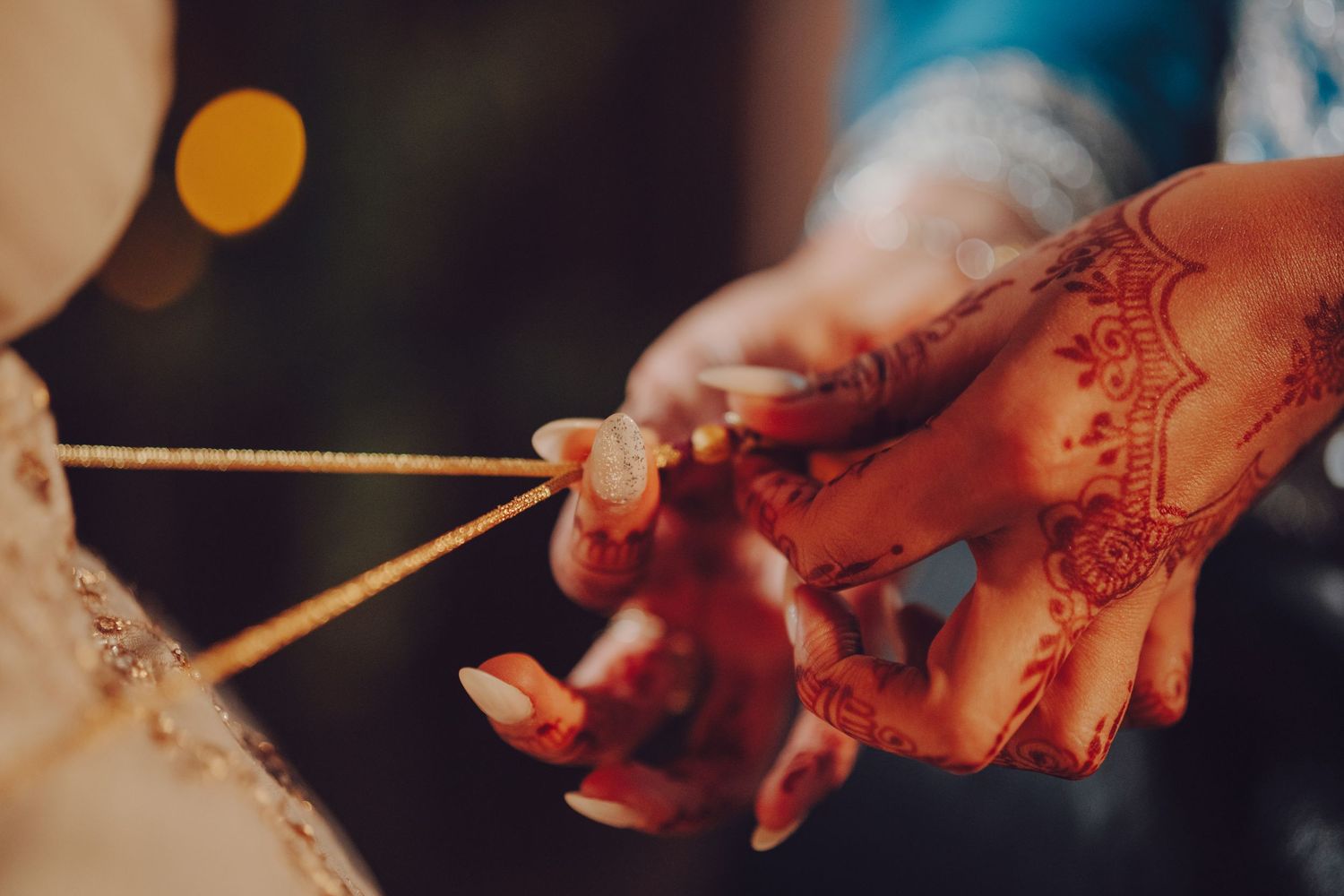 Close-up of hands decorated with henna during traditional Indian wedding ceremony.