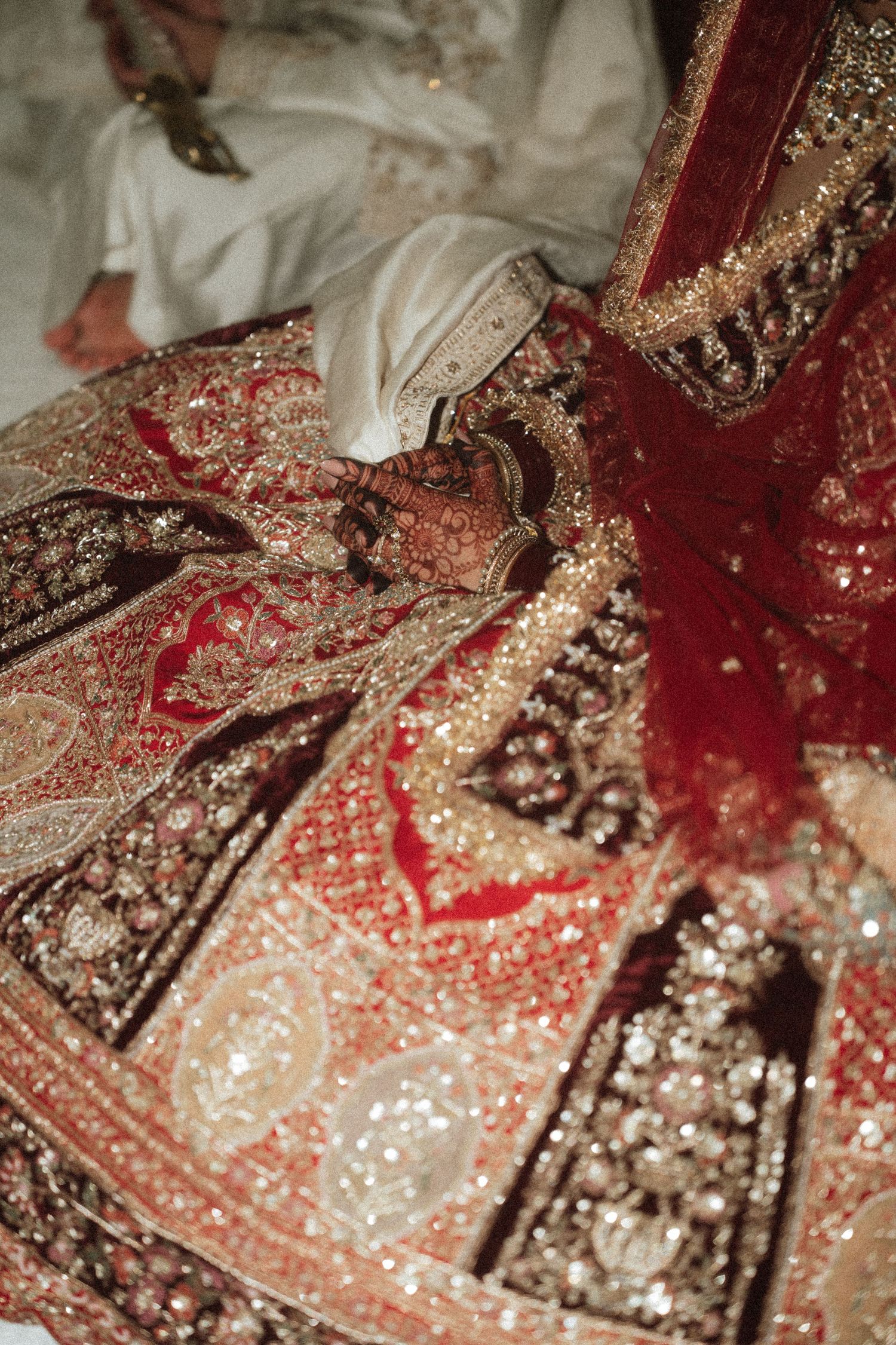 Close-up detail of heavily embellished Indian bridal lehenga with red and gold embroidery work.