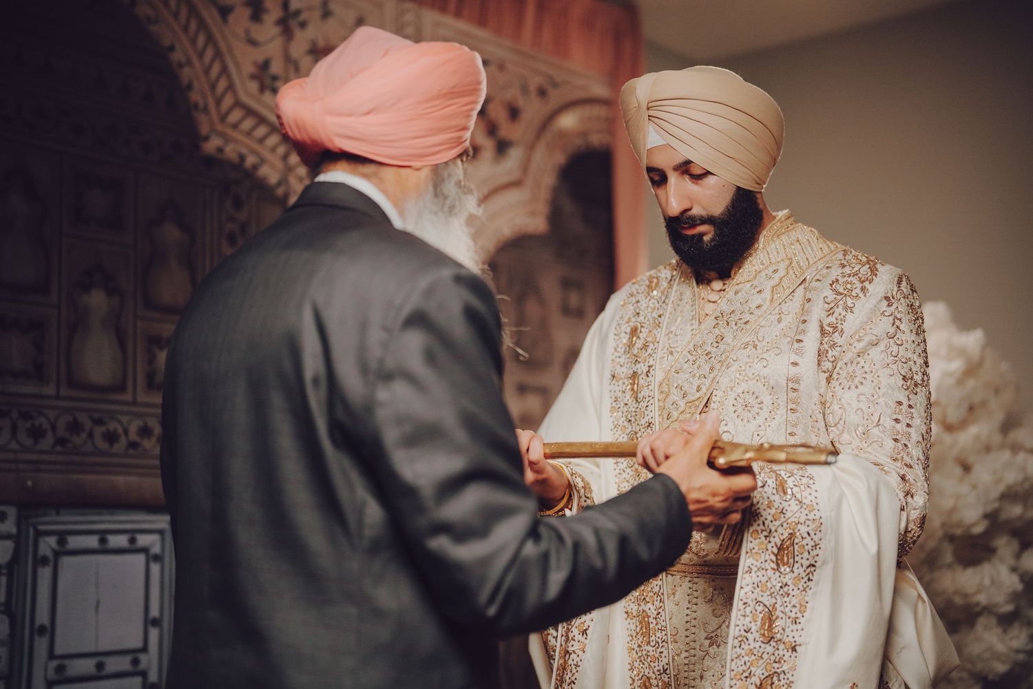 Traditional Sikh wedding ceremony taking place indoors with ornate decorative backdrop.