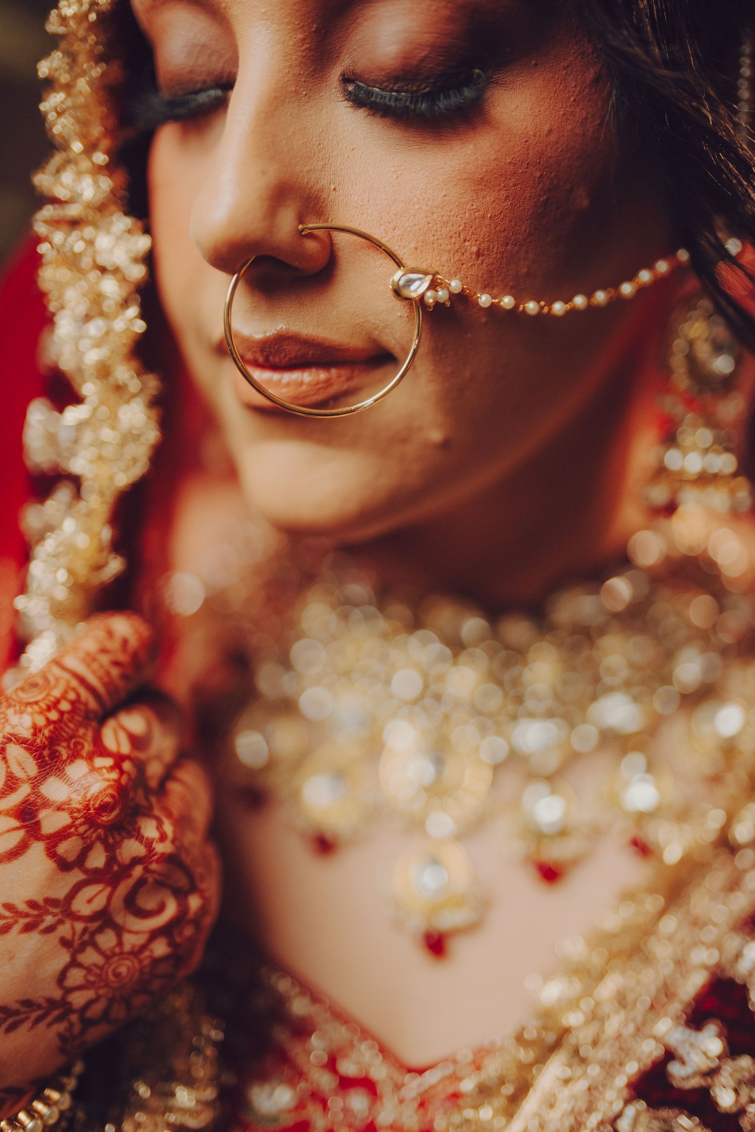 Close-up detail of bridal jewelry and mehndi designs with sparkling gold accents and nose ring.