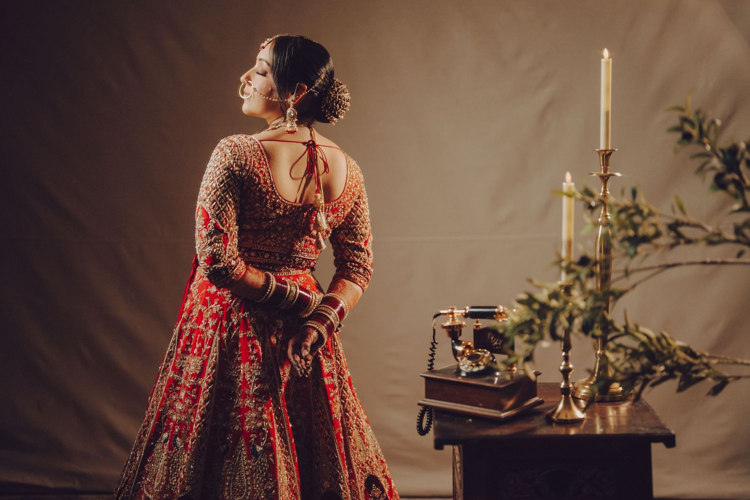 Traditional Indian bridal attire featuring an ornate red and gold lehenga with intricate embroidery details.