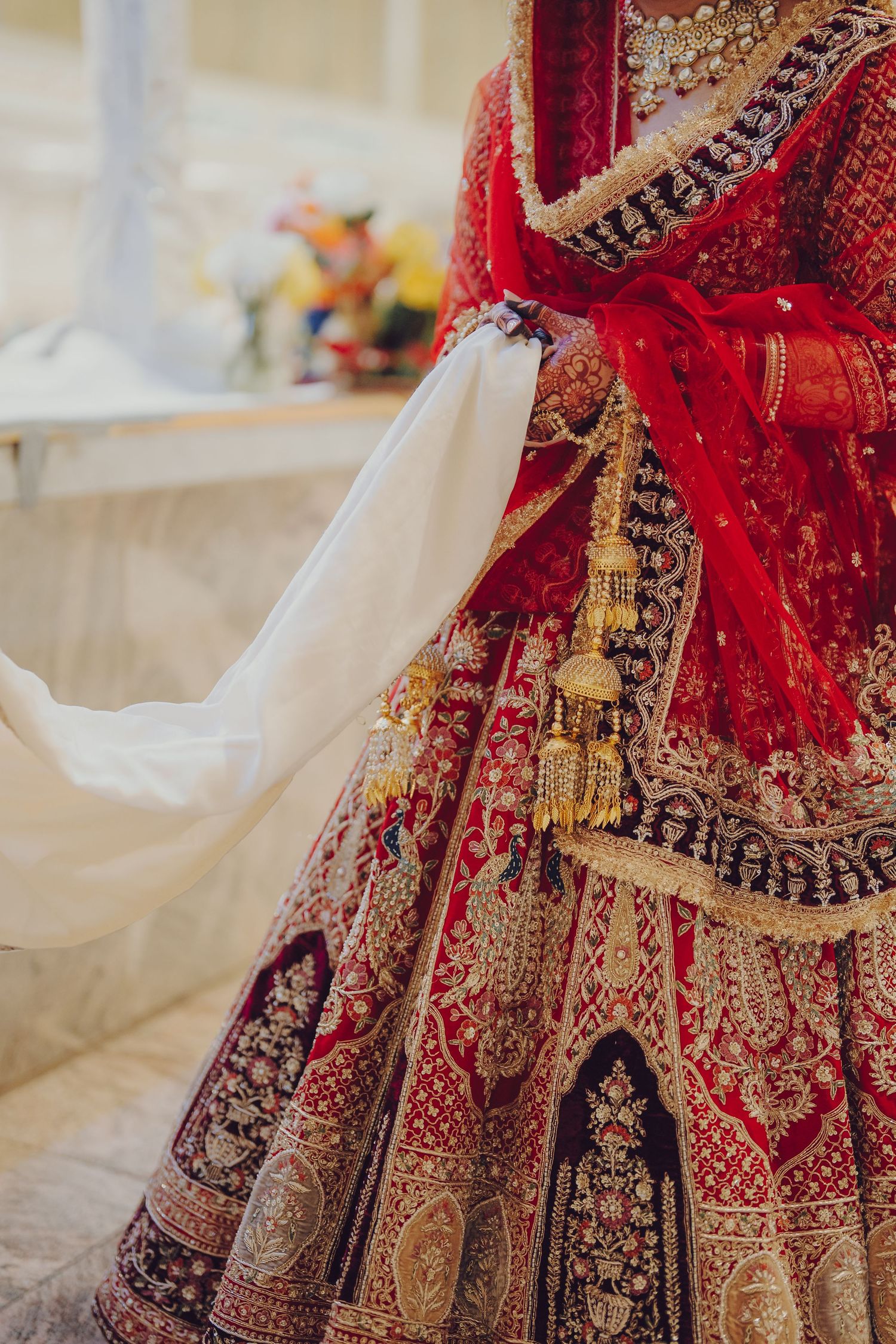 Detailed view of a red and gold embroidered Indian bridal lehenga with intricate patterns.