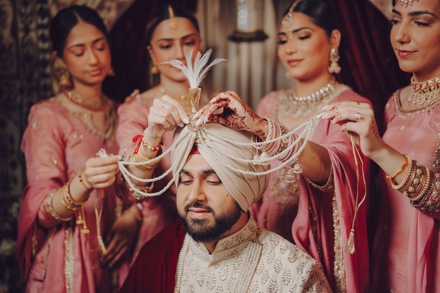 Traditional Indian wedding ceremony showing hands performing rituals in pink and gold themed decor.
