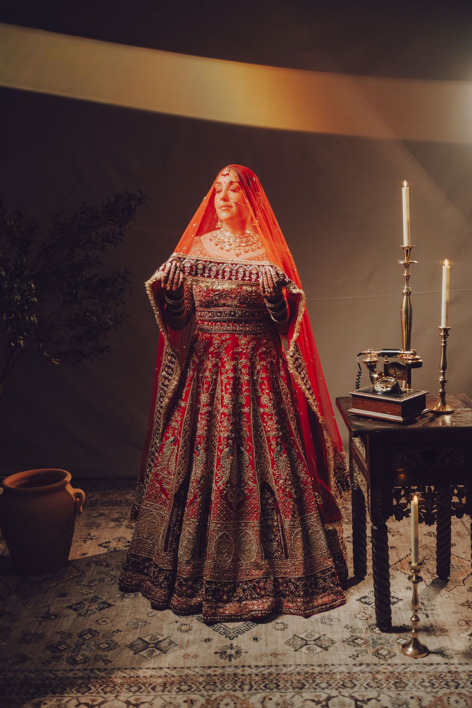 Traditional Indian bridal attire featuring an ornate red lehenga and veil with candlelit ambiance.