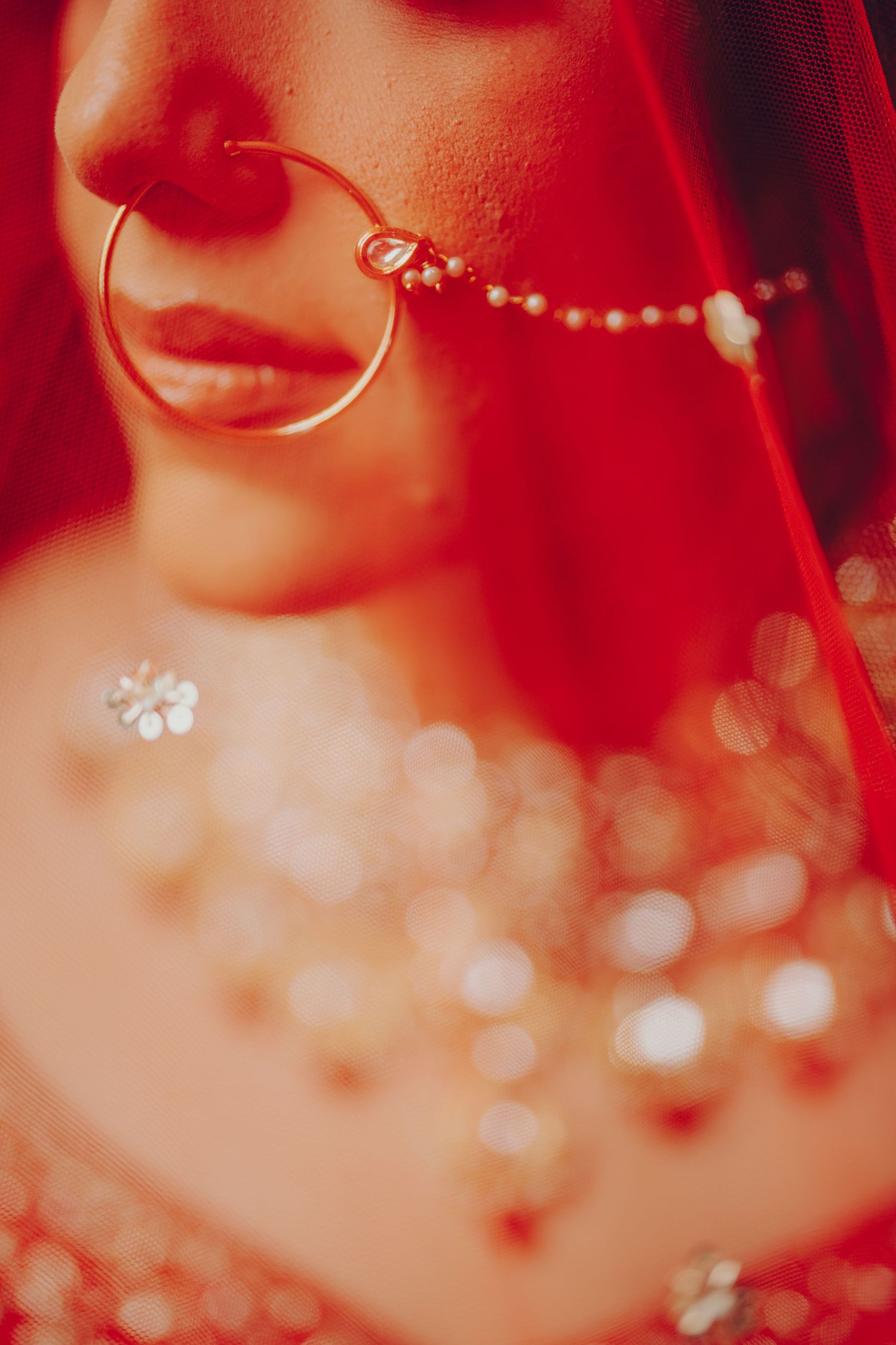 Artistic close-up shot of traditional Indian bridal jewelry in red tones.