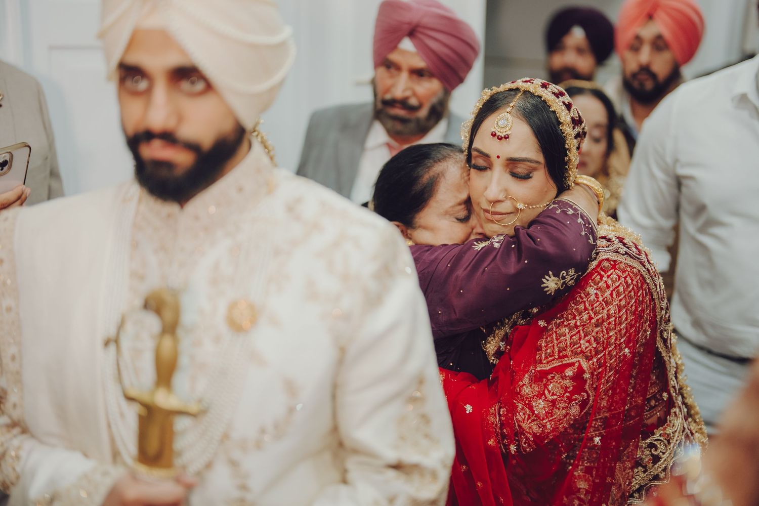 An emotional moment during a Sikh wedding ceremony with attendees in traditional attire.