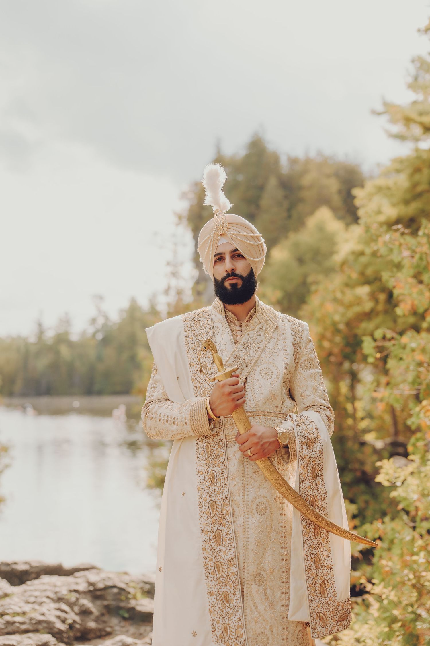 Traditional Indian wedding attire featuring an ornate white and gold sherwani by a lakeside setting.