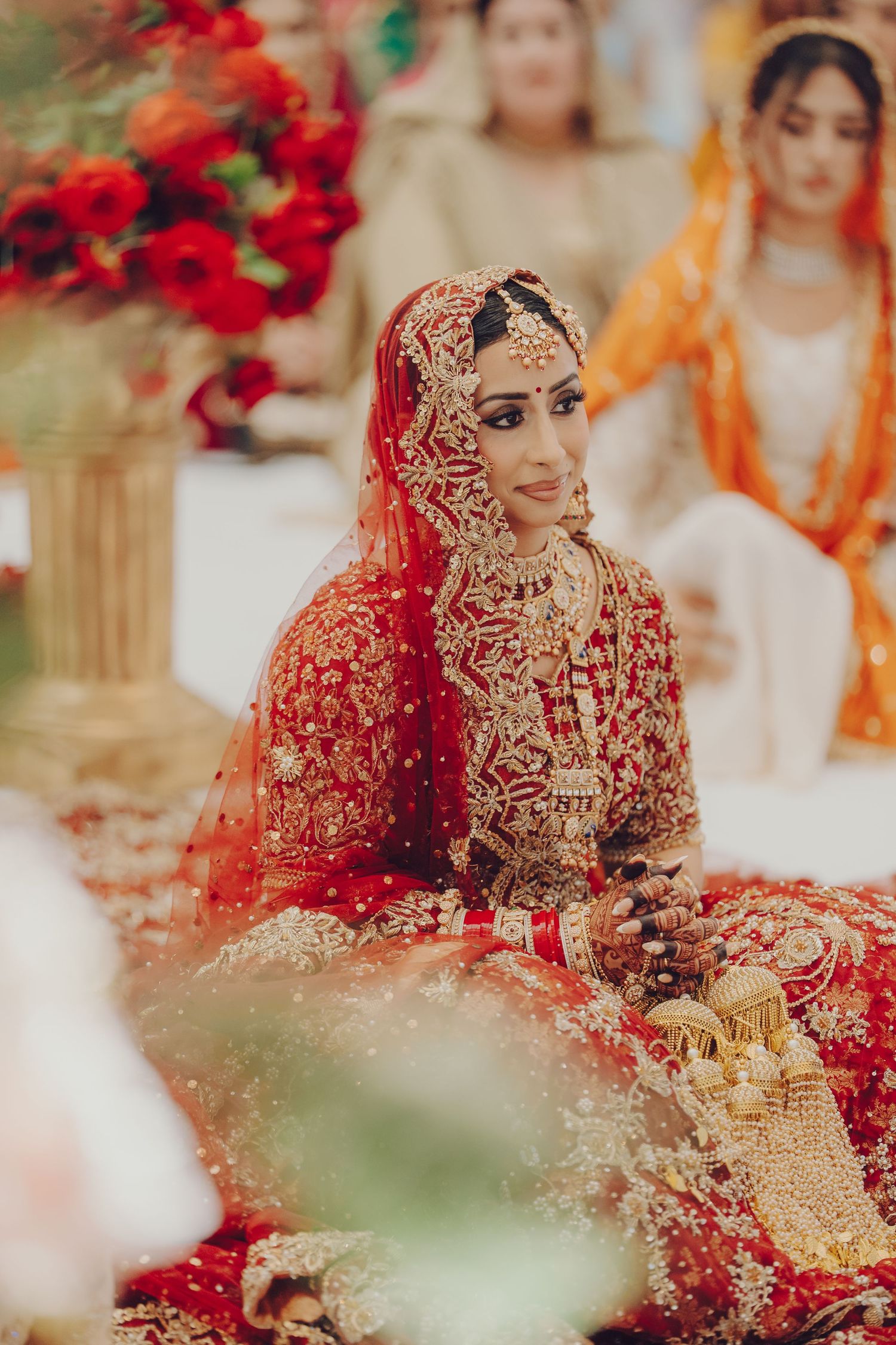 Ornate red and gold traditional bridal attire with detailed embroidery and jewelry at a wedding ceremony.