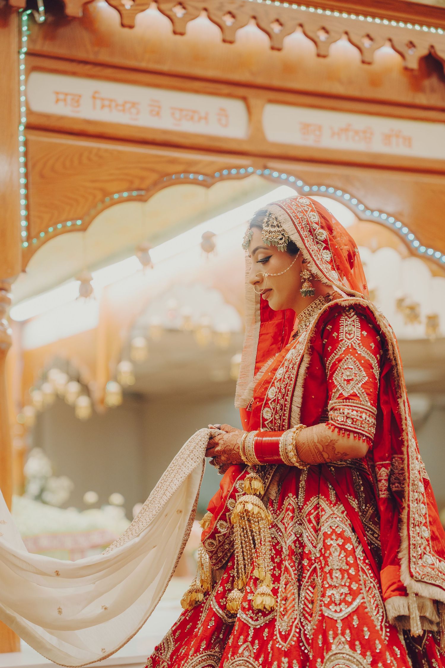 Ornate red and gold bridal lehenga with intricate embroidery details during traditional Indian wedding ceremony.