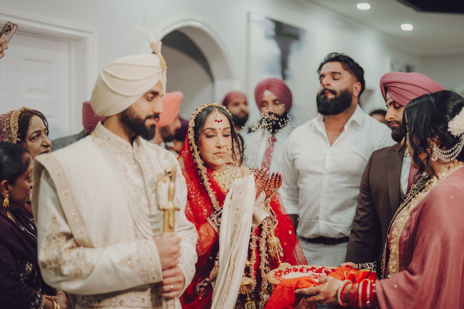 Indoor wedding celebration with traditional Sikh ceremony customs and decorations.