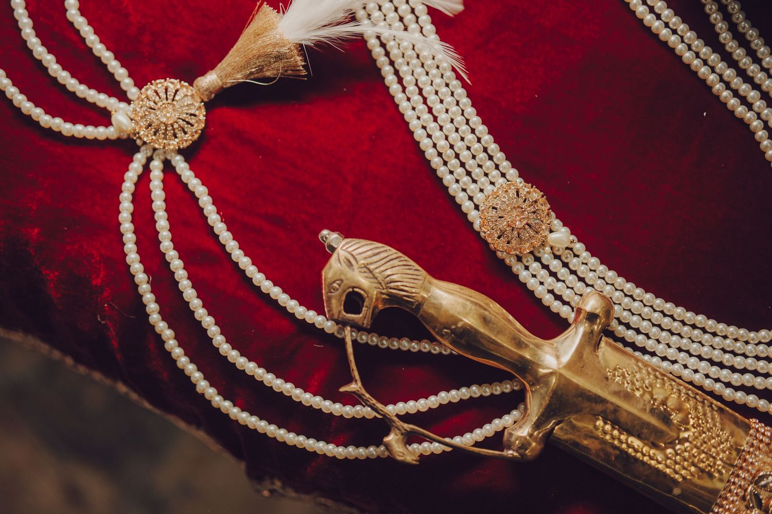 Close-up view of pearl necklaces and gold jewelry displayed against a deep red velvet background.