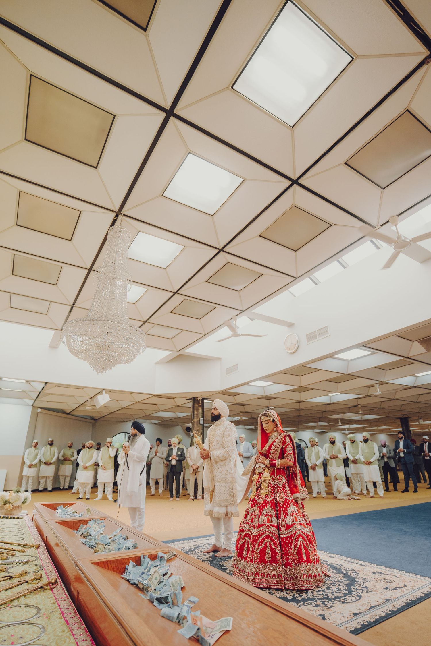 Wide view of a traditional wedding ceremony space with decorative red garments and seated guests.
