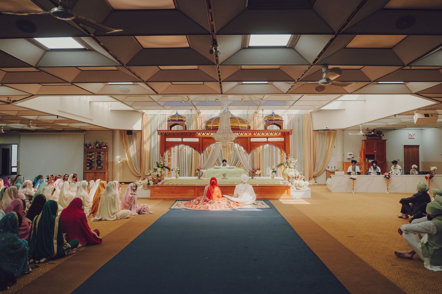 Wide angle view of a wedding ceremony hall with guests seated on the floor in rows.