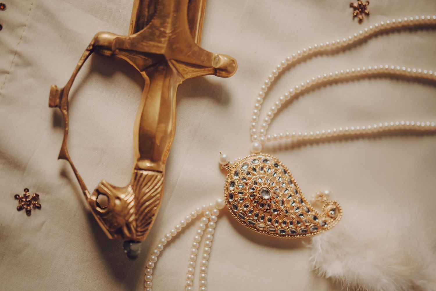 Wedding accessories including pearl necklaces and gold heels arranged on a beige surface.